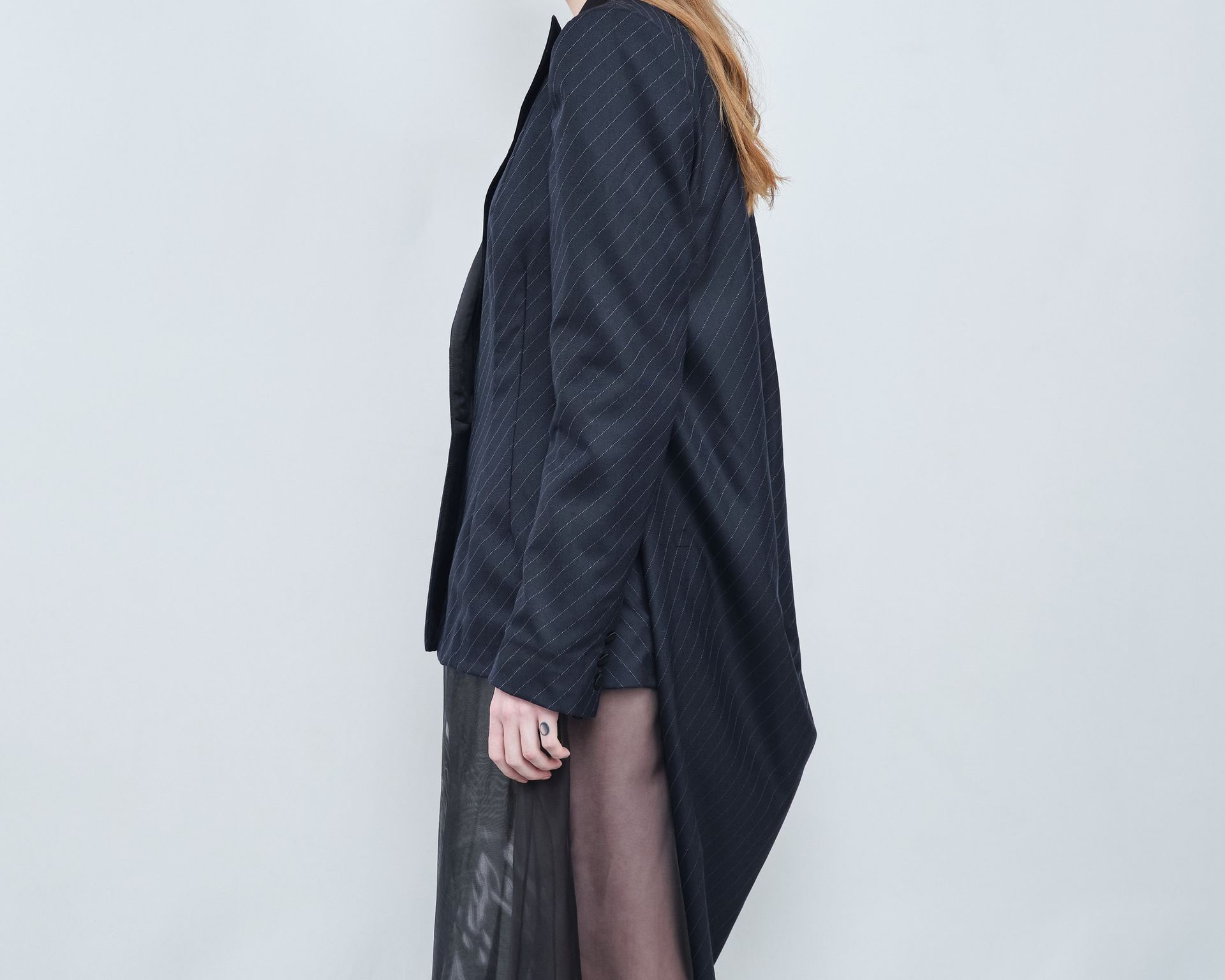 A woman is wearing a black tuxedo jacket and a black dress.