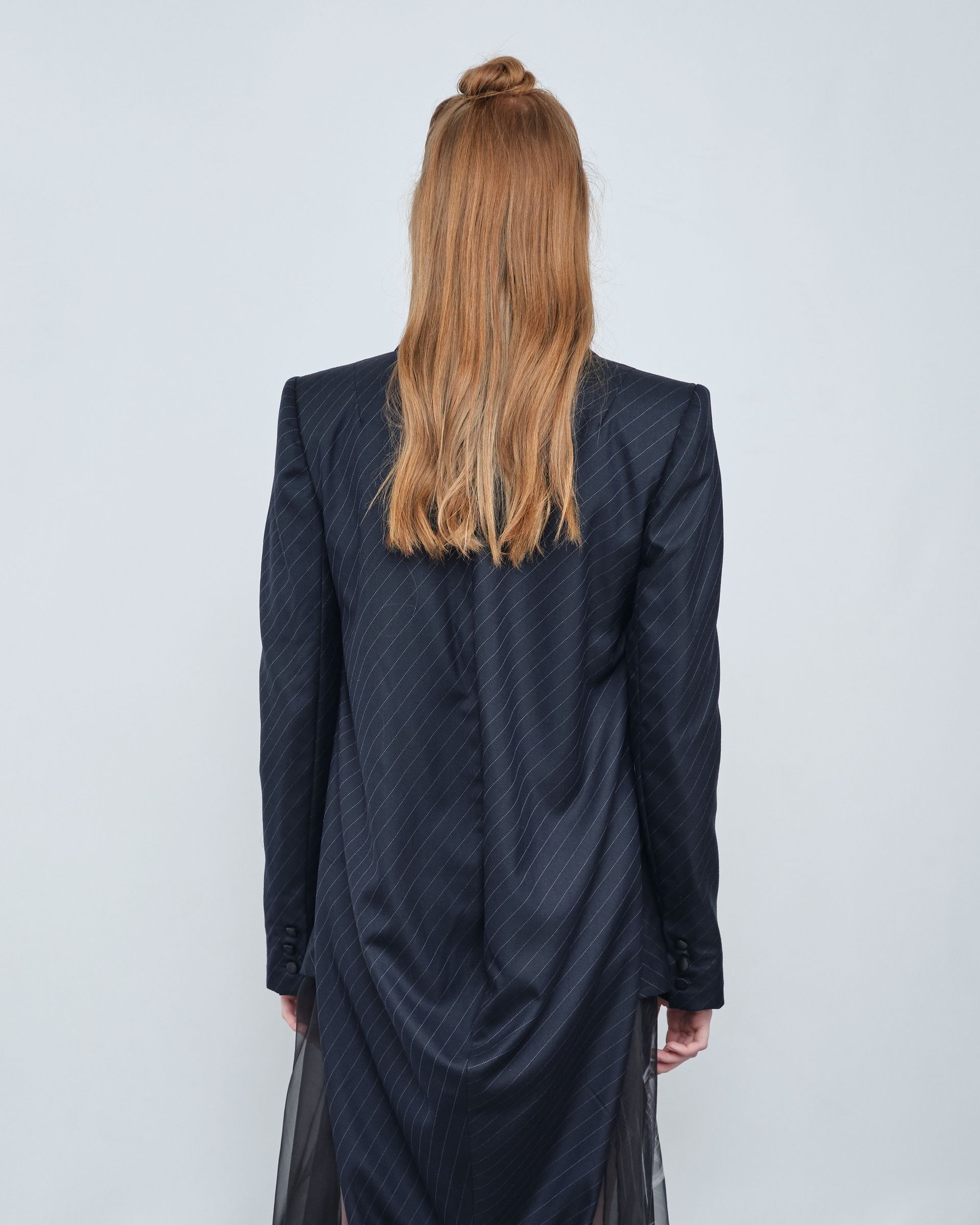 The back of a woman wearing a black jacket and a black dress.