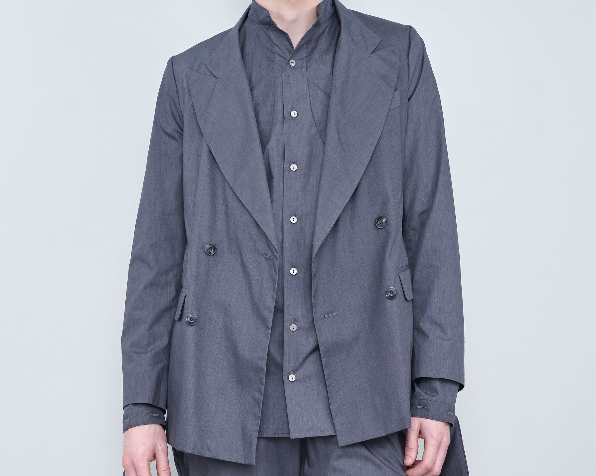 A man wearing a grey jacket and a grey shirt