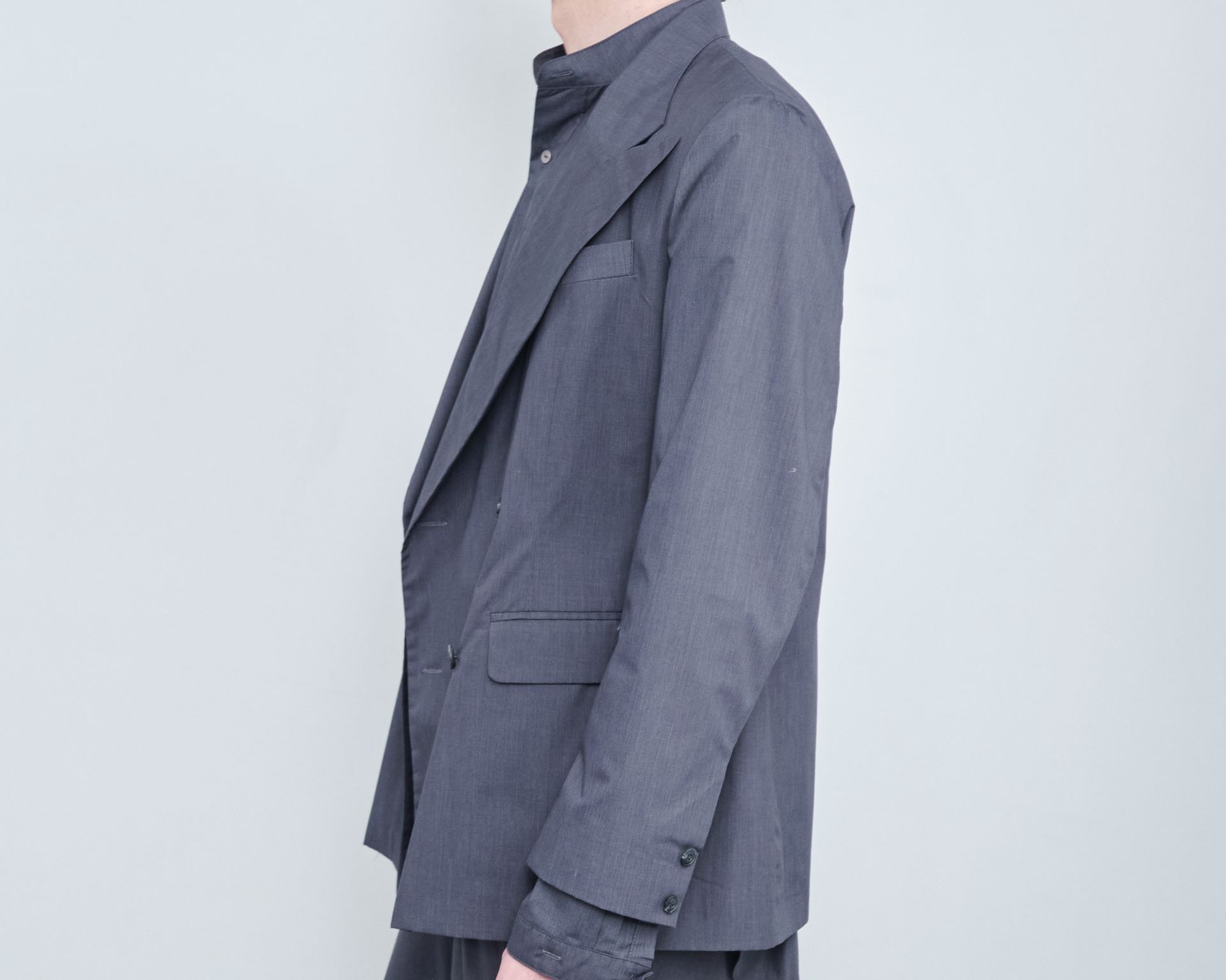 A man is wearing a grey suit jacket and a grey shirt.