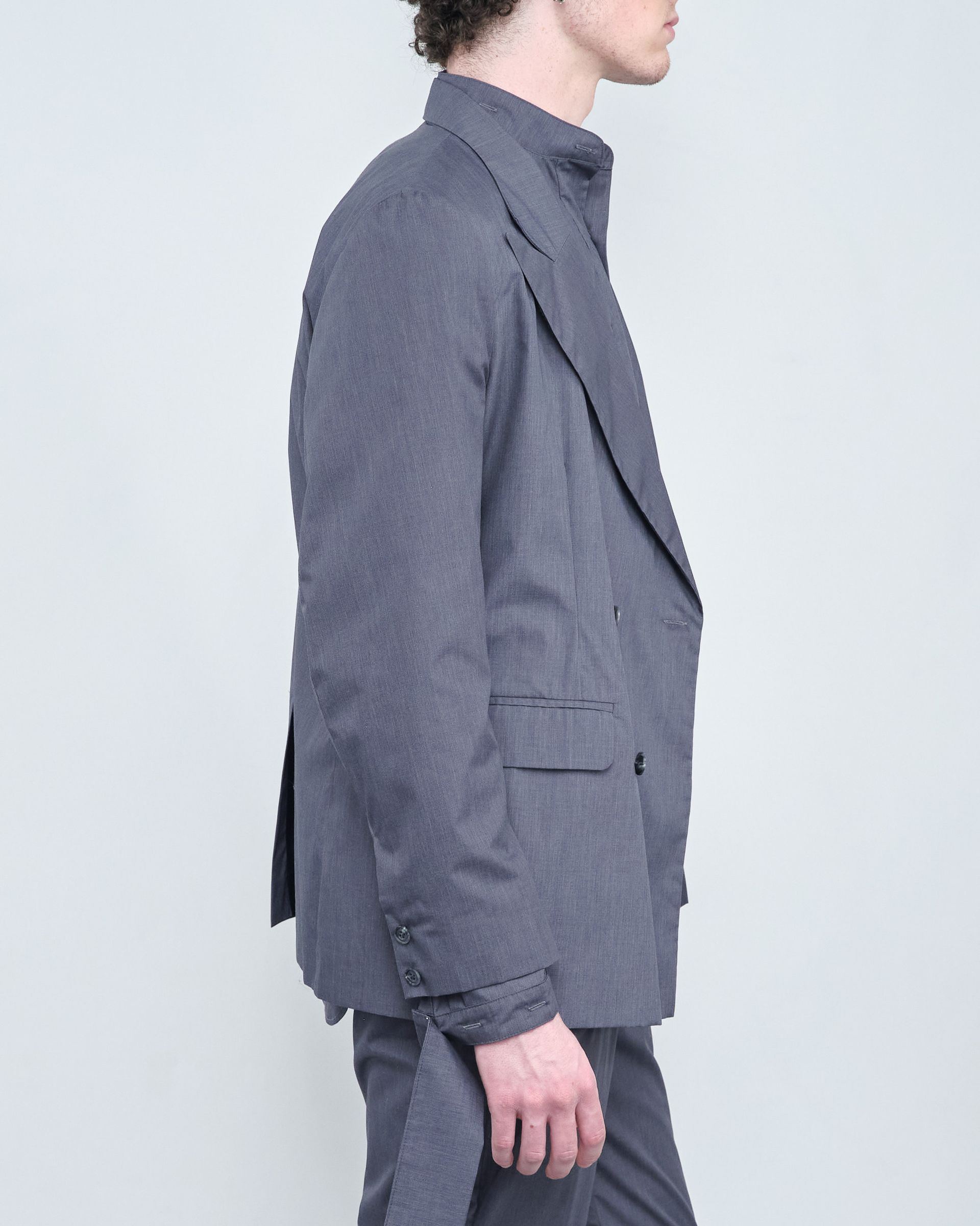 A man is wearing a grey suit jacket and pants