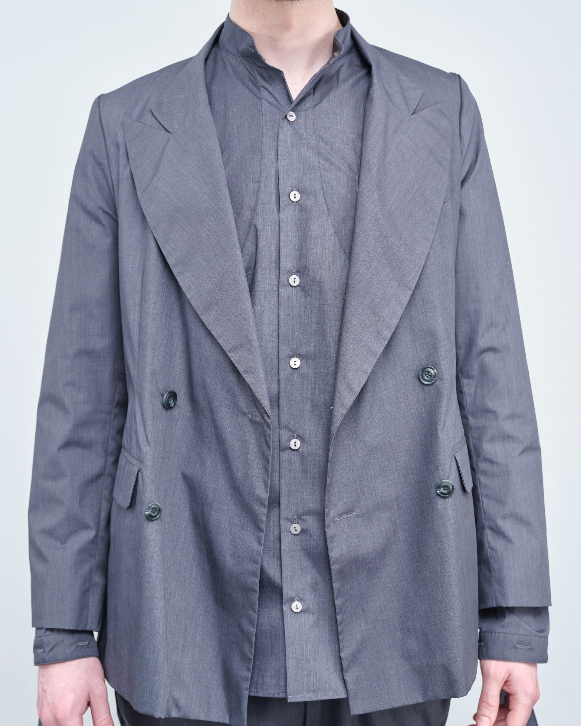 A man wearing a grey jacket and a grey shirt