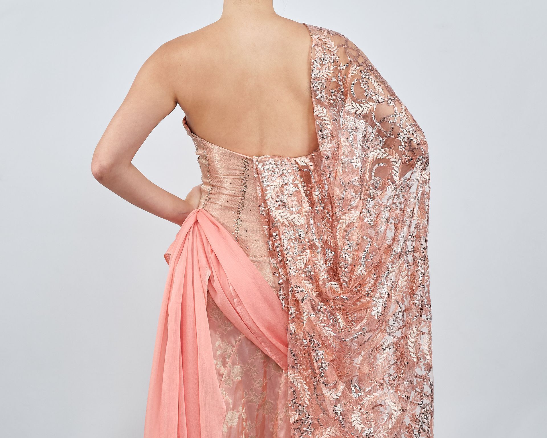 The back of a woman wearing a pink dress with a cape.