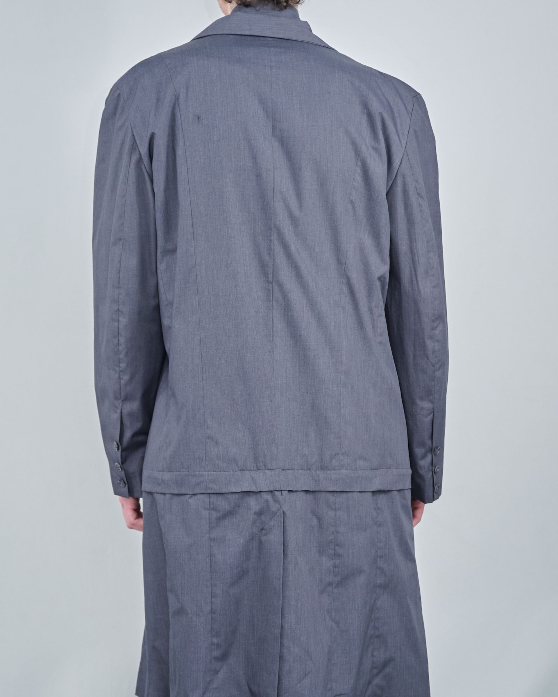 The back of a person wearing a grey jacket and skirt