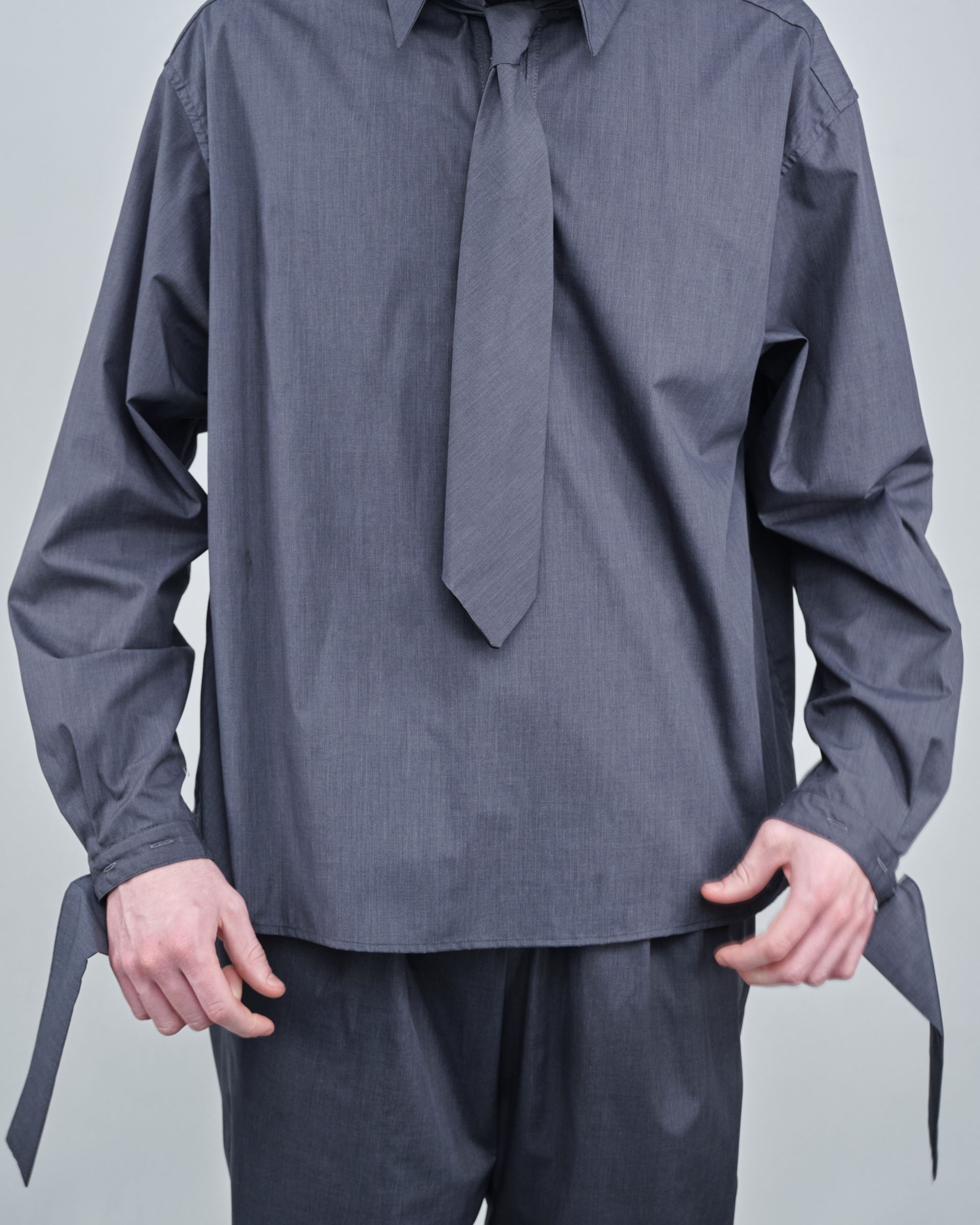 A man is wearing a gray shirt and tie