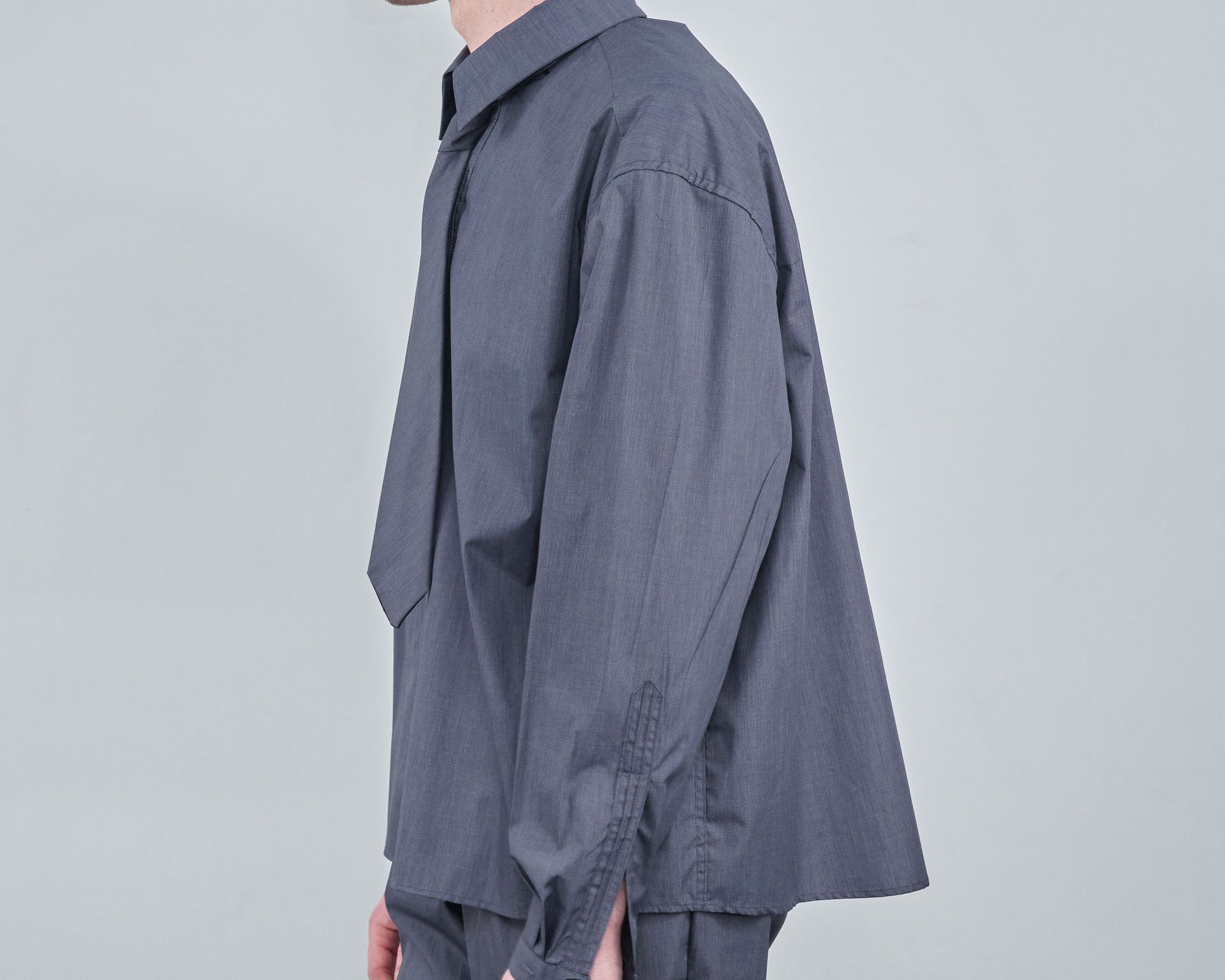 A man is wearing a gray shirt and tie.