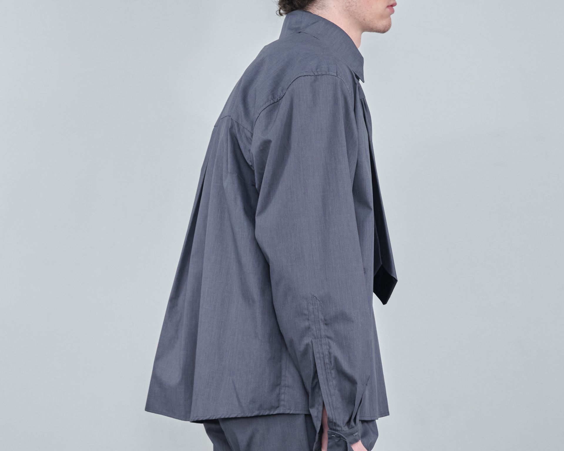 A man wearing a gray shirt and tie