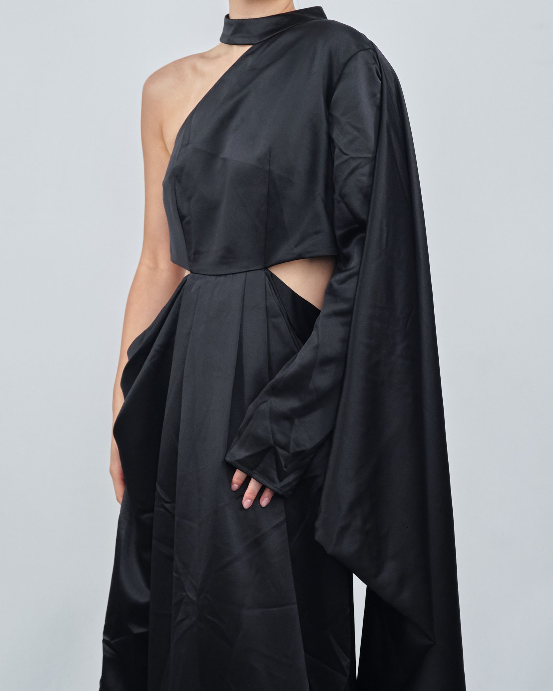 A woman is wearing a black one shoulder dress