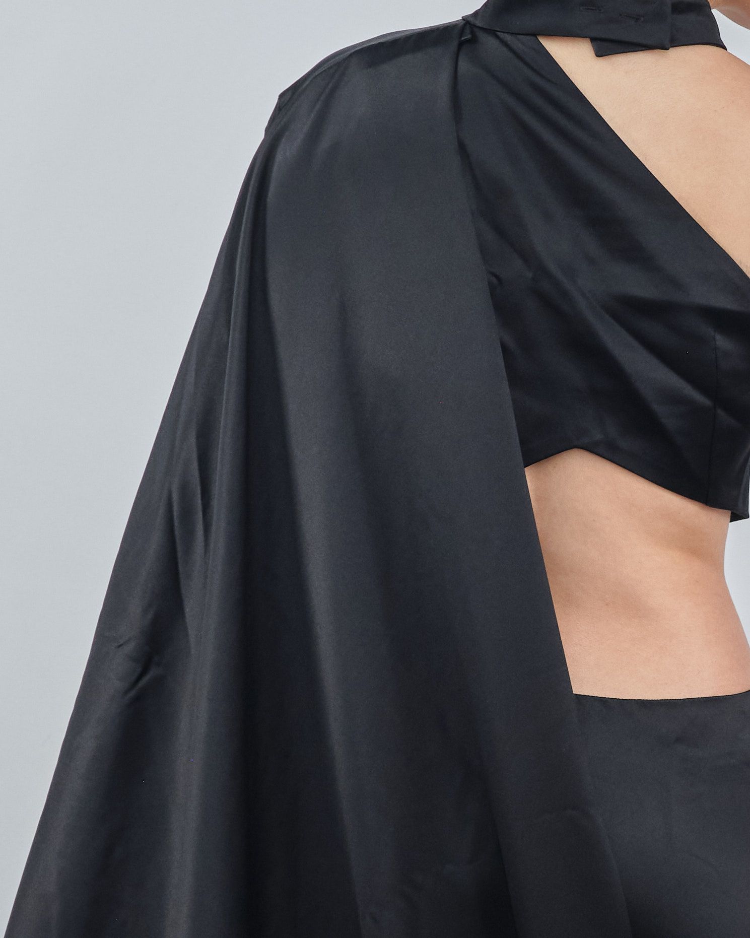 A woman wearing a black cape and a black crop top