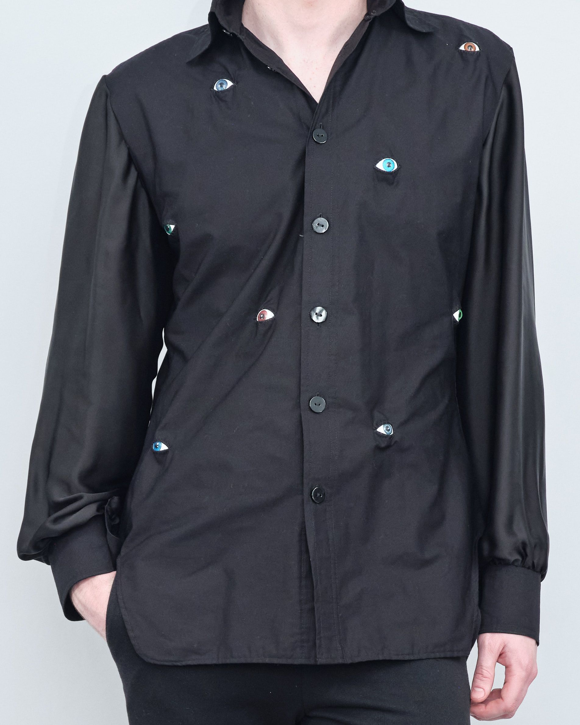 A man wearing a black shirt with buttons on the sleeves