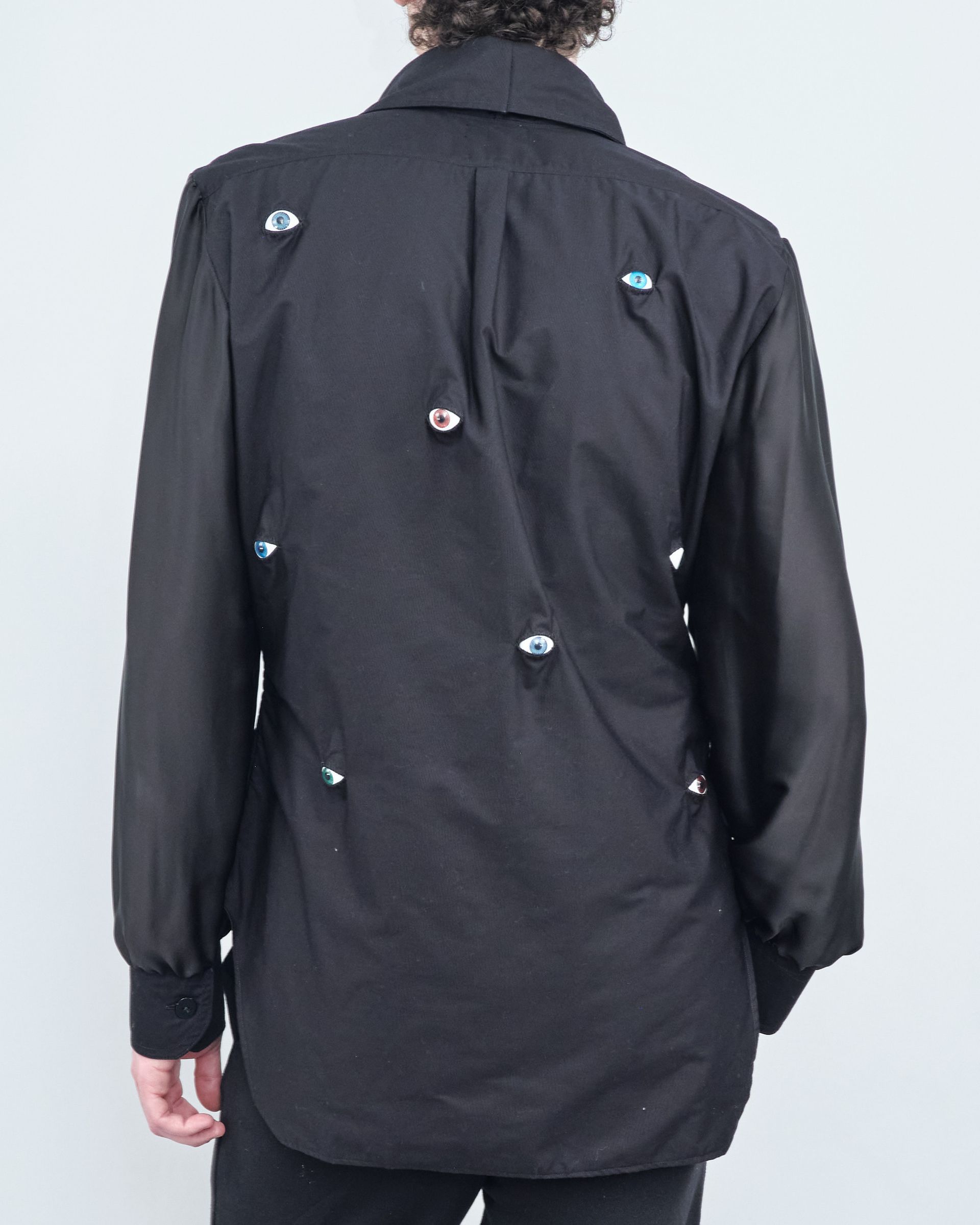 A man wearing a black shirt with buttons on the back