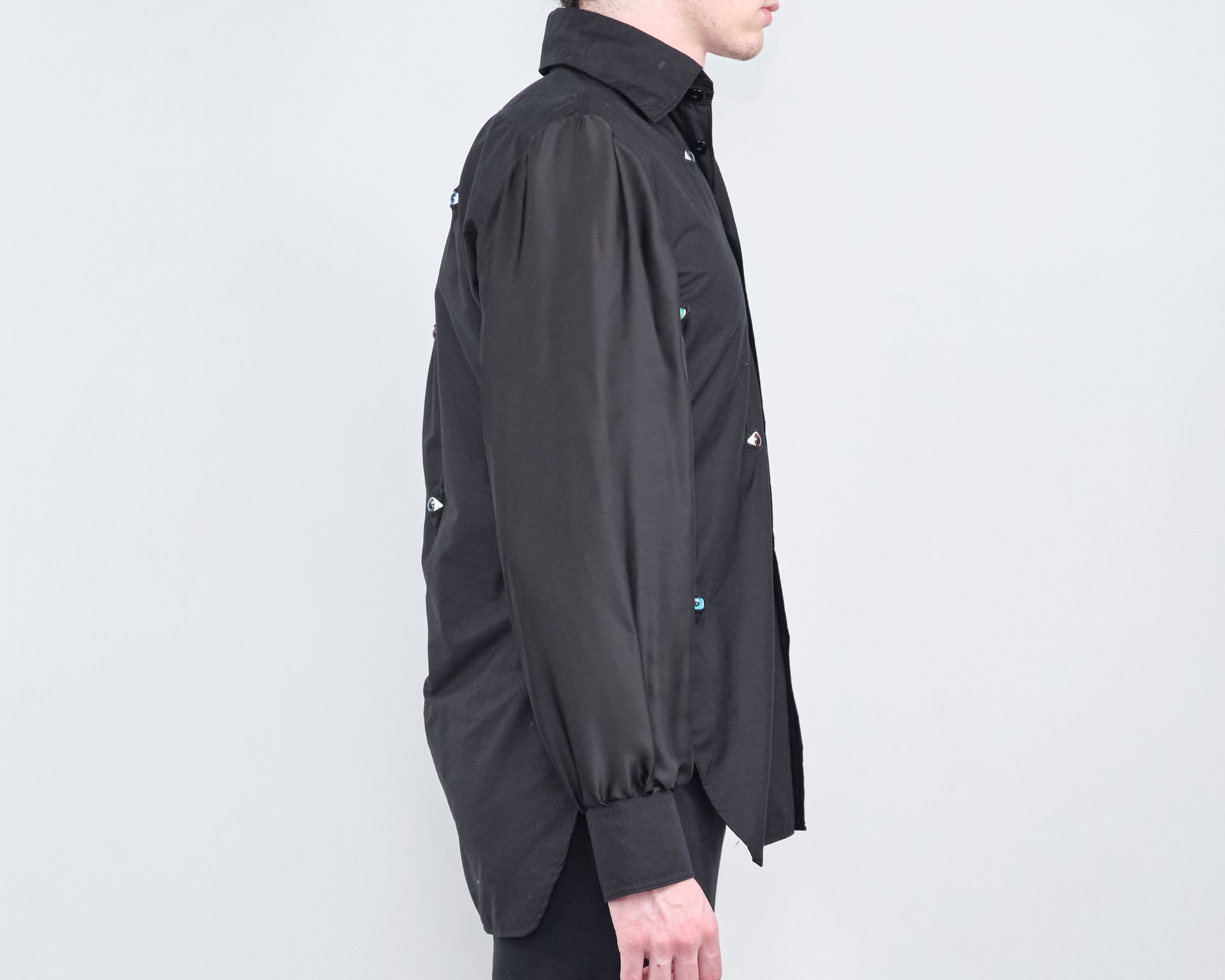 A man wearing a black shirt with buttons on the sleeves