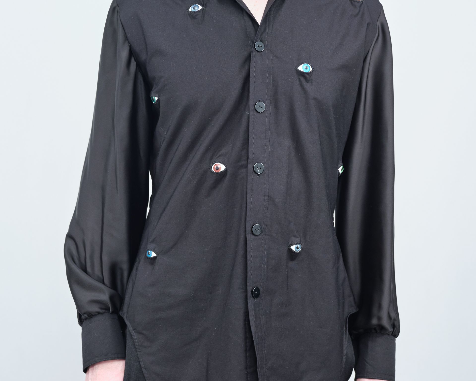A person wearing a black shirt with buttons on it