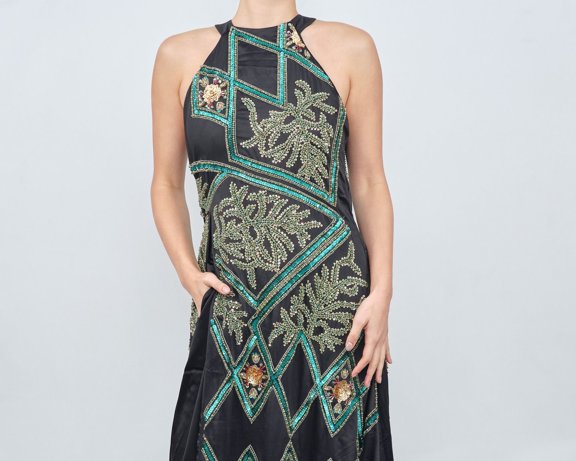 A woman is wearing a black and green dress with a halter neckline