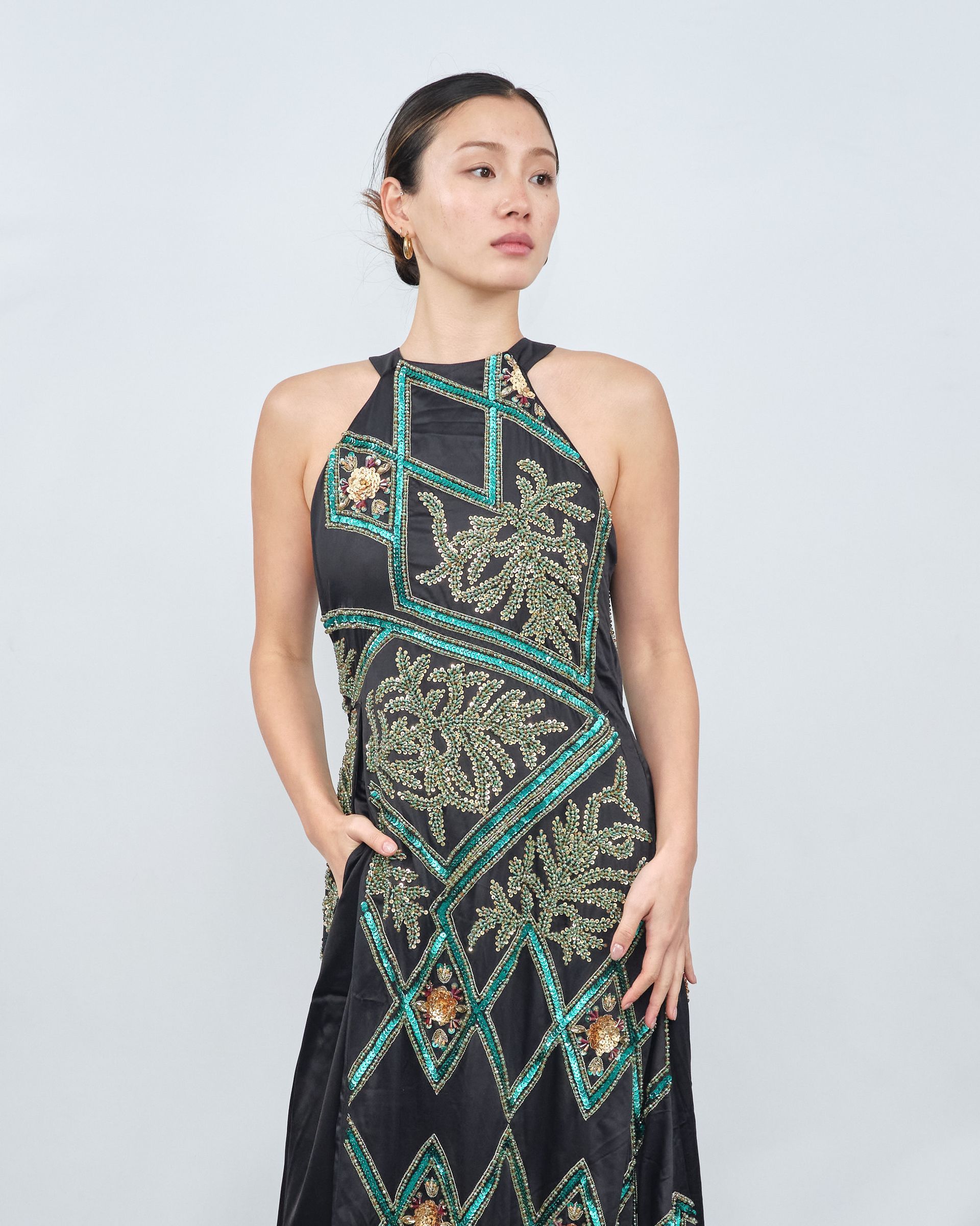 A woman is wearing a black and green dress with a halter neckline.