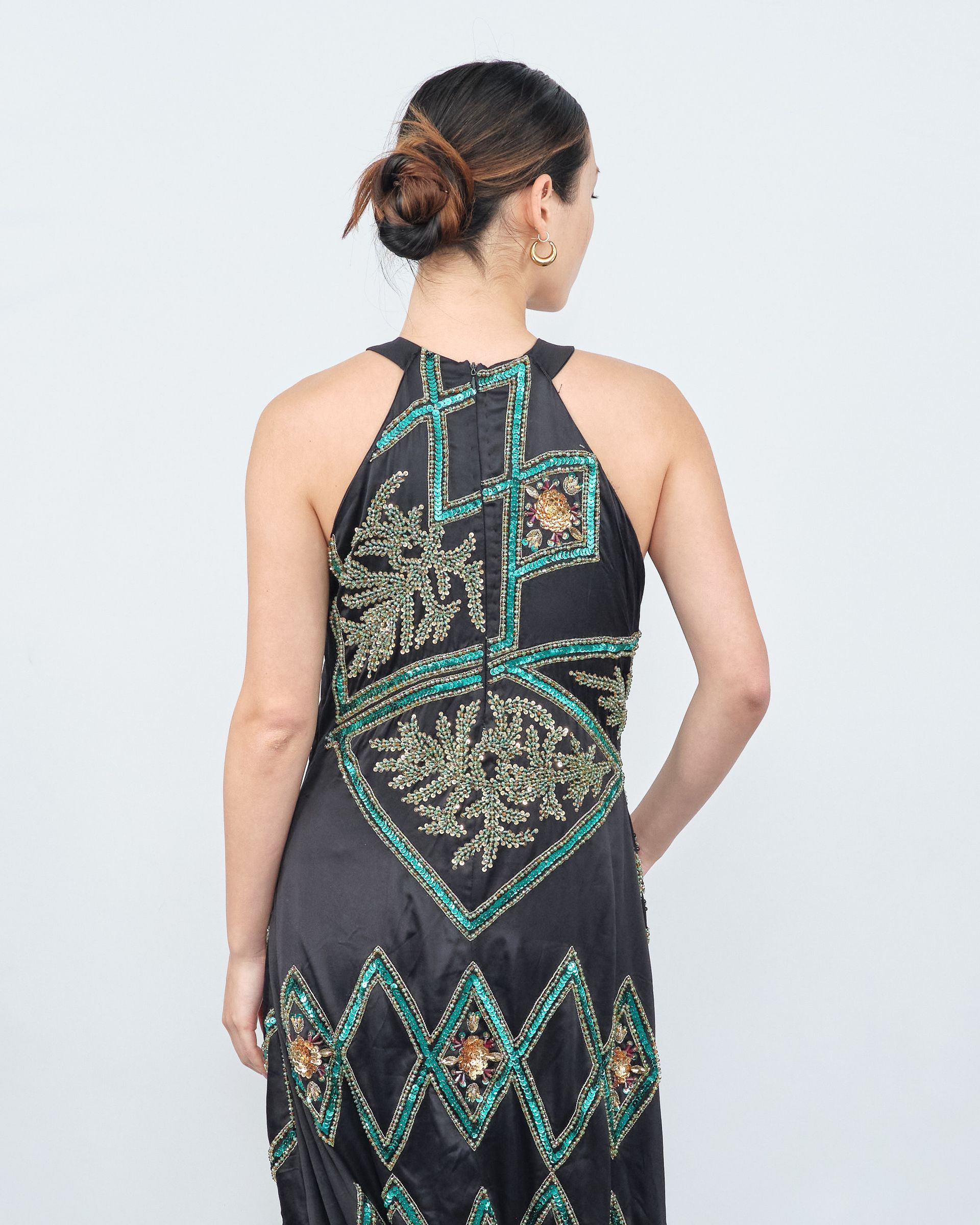 The back of a woman wearing a black dress with green beads.