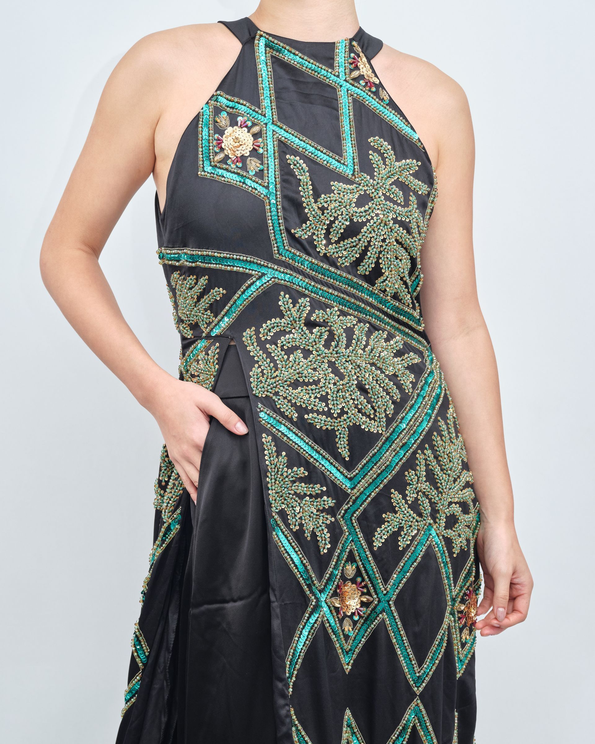 A woman is wearing a black and green dress with a halter neckline