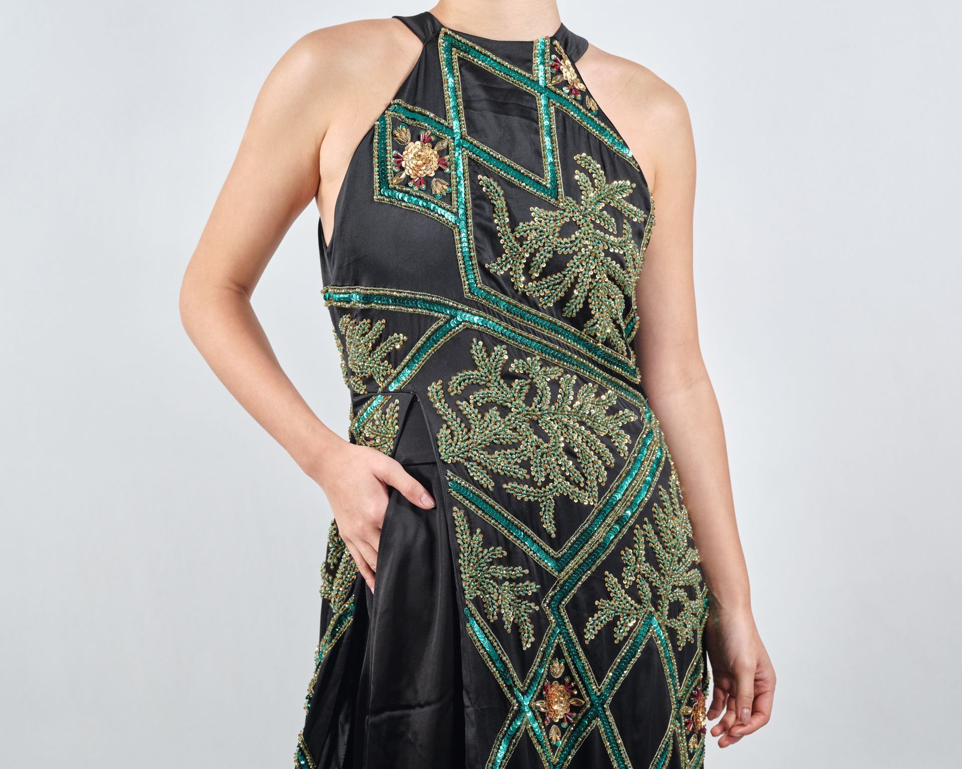 A woman is wearing a black and green dress with a halter neckline.
