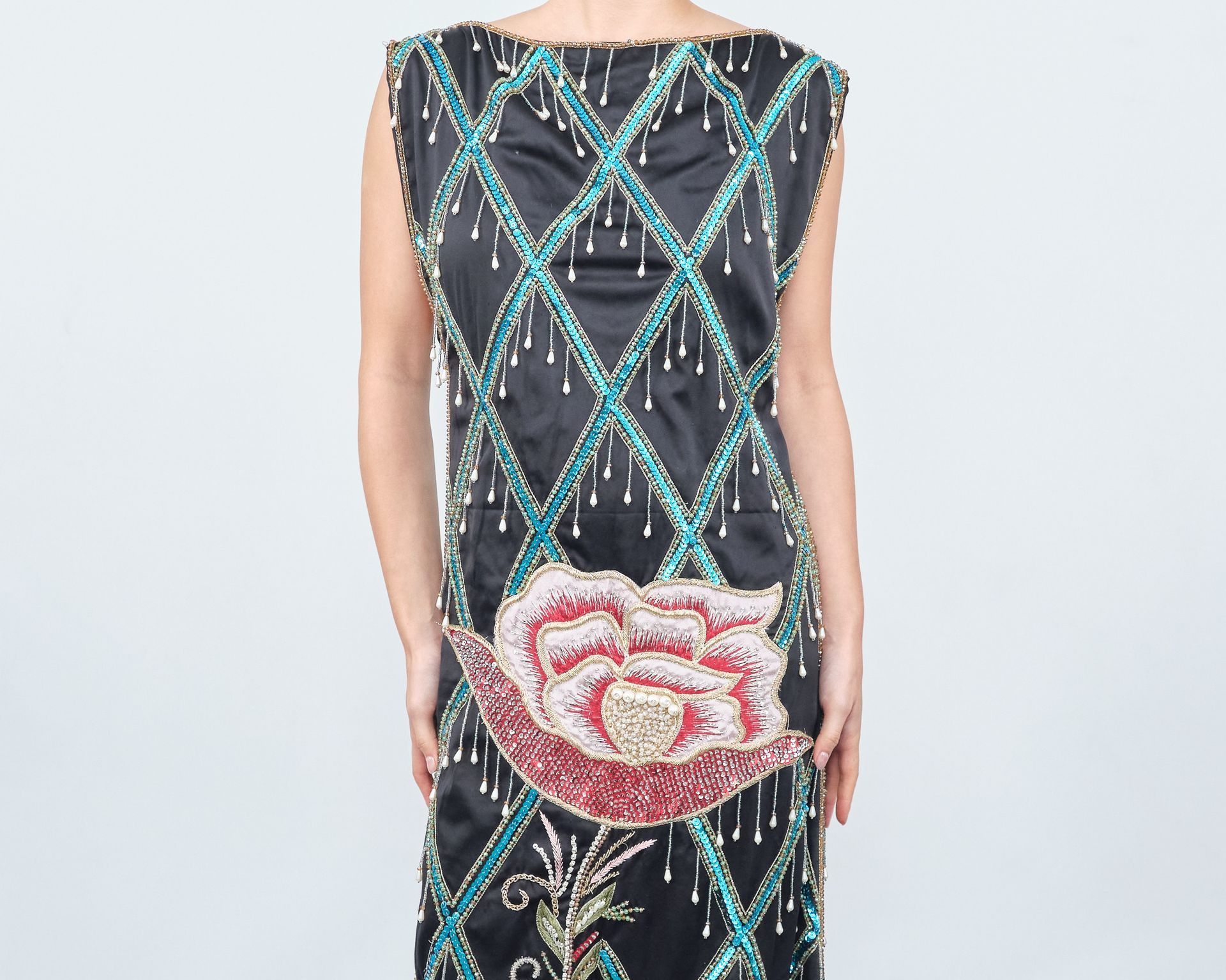 A woman is wearing a black dress with a flower on the back.