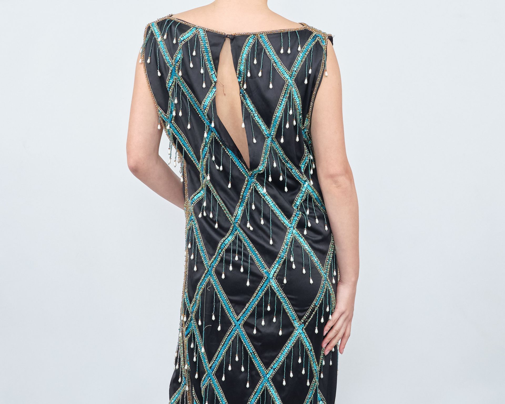 The back of a woman wearing a black dress with blue beads