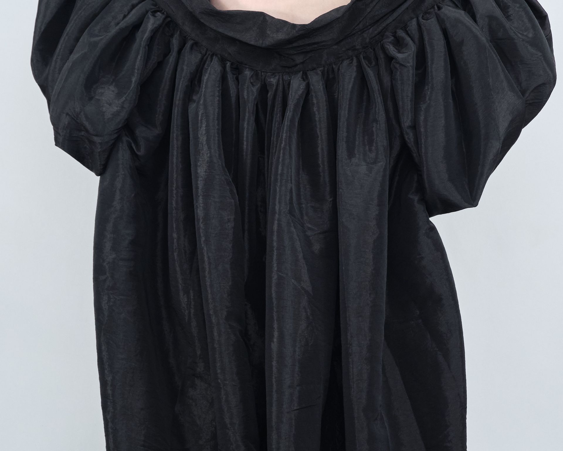 A woman is wearing a black dress with puffed sleeves