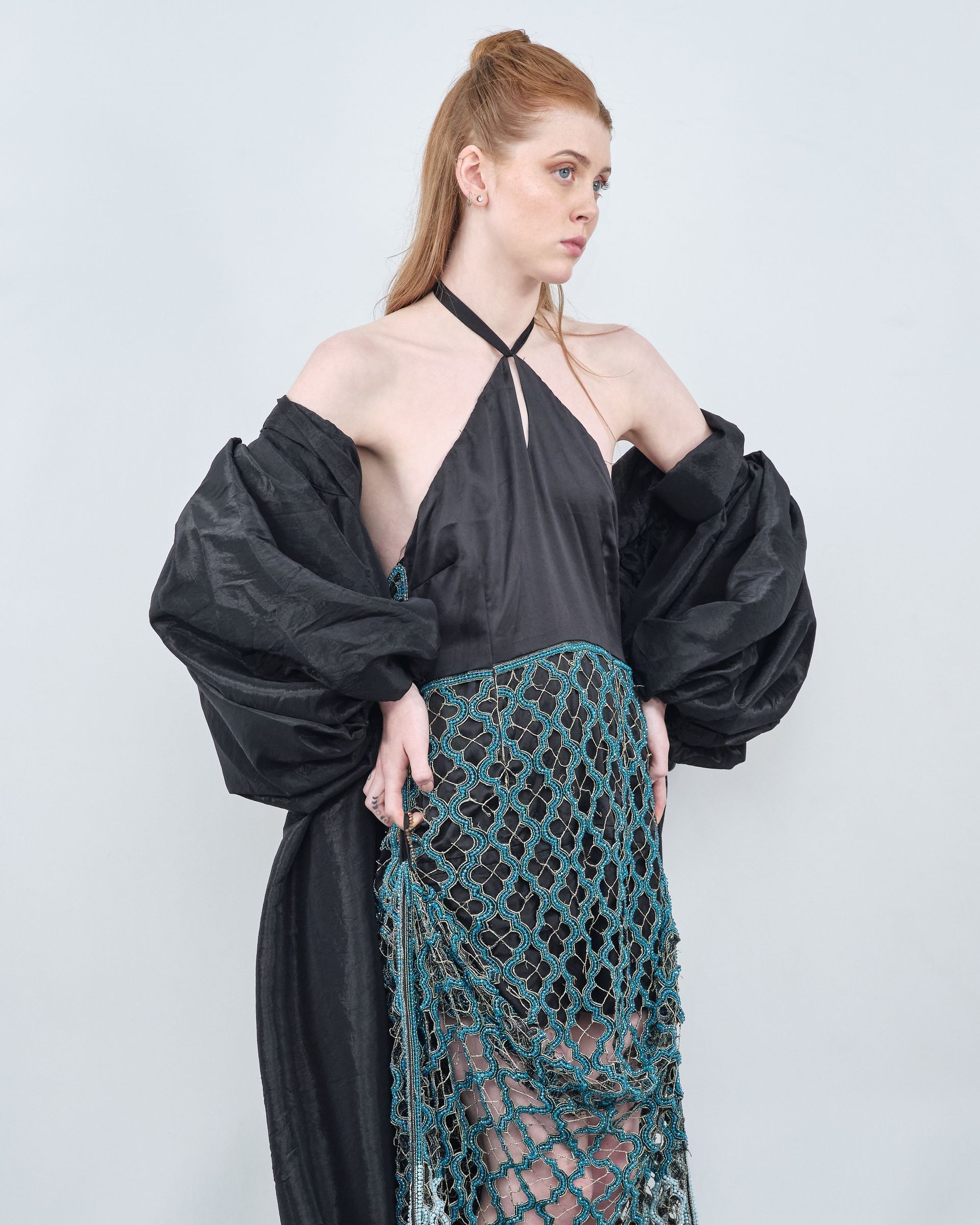 A woman is wearing a black top and a blue skirt.