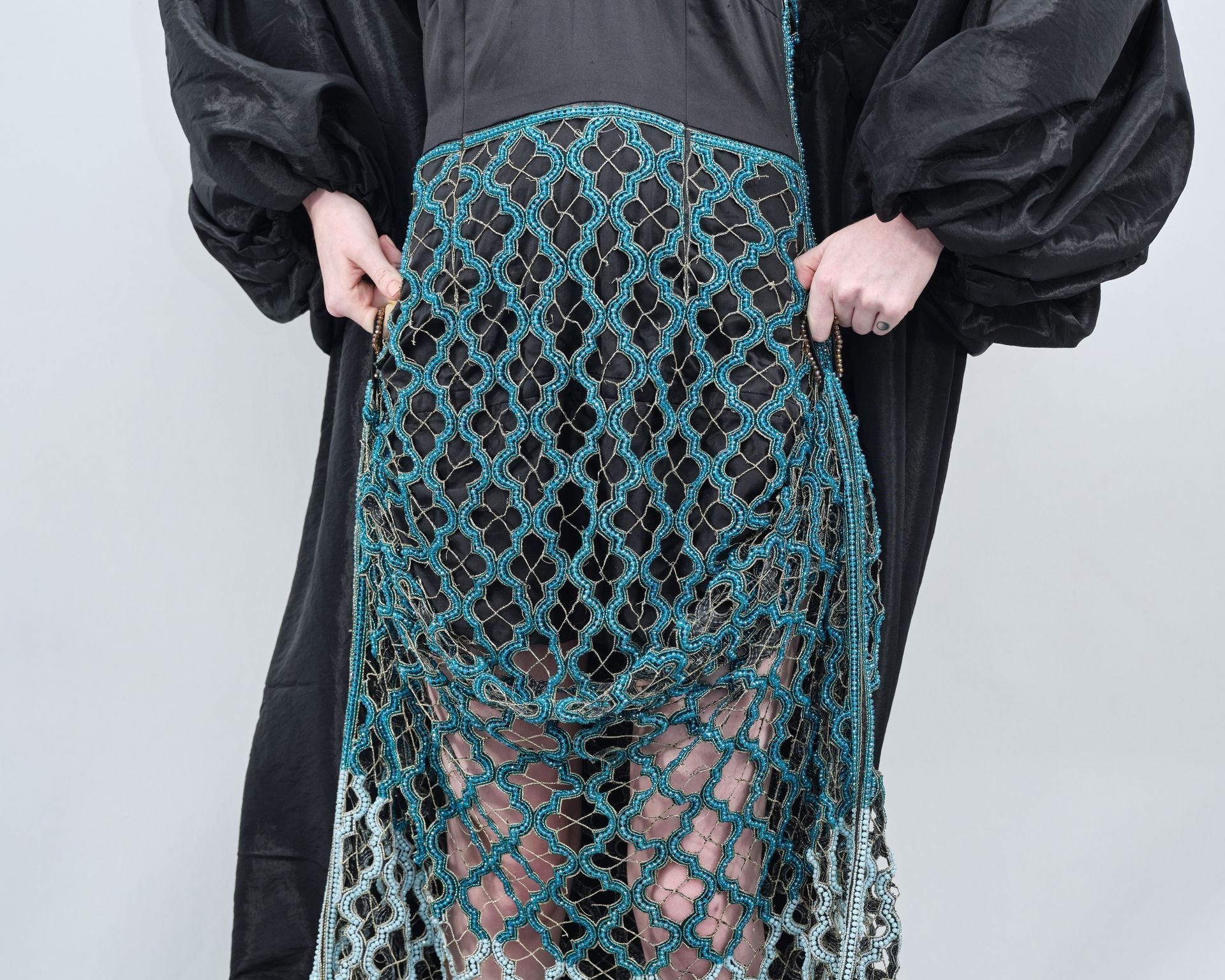 A woman wearing a black dress and a blue skirt