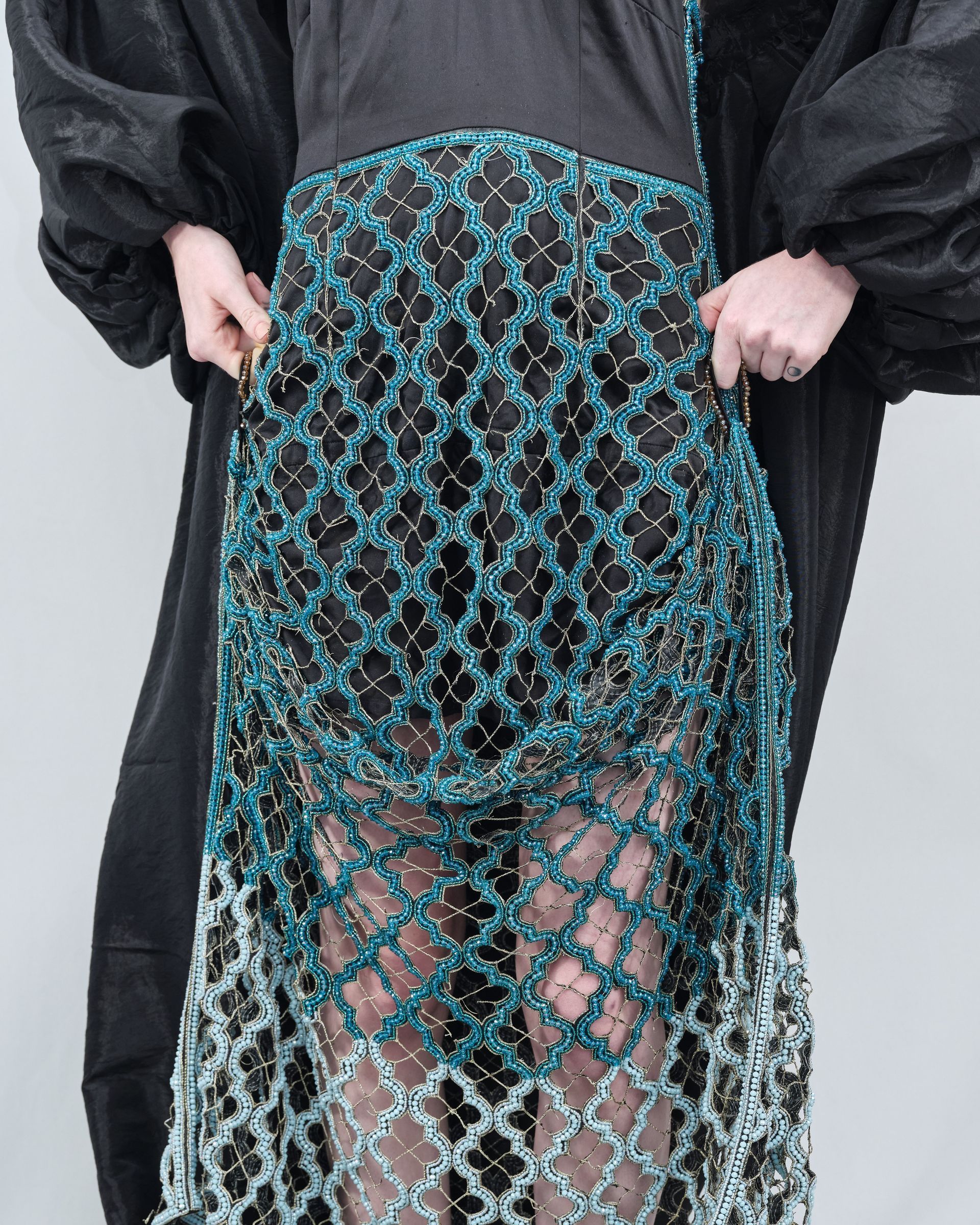 A woman in a black dress is holding a blue purse