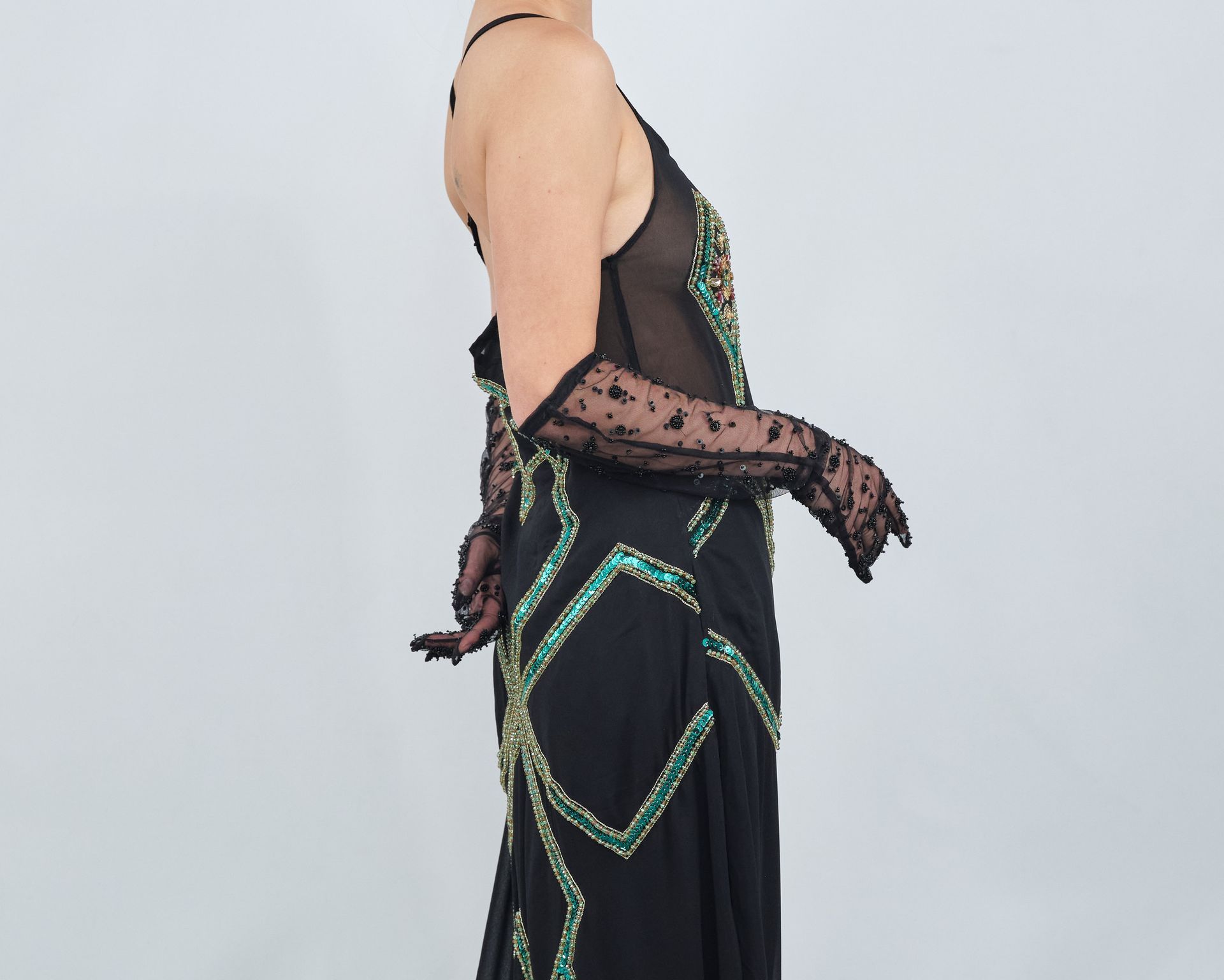 A woman is wearing a black dress and black gloves.