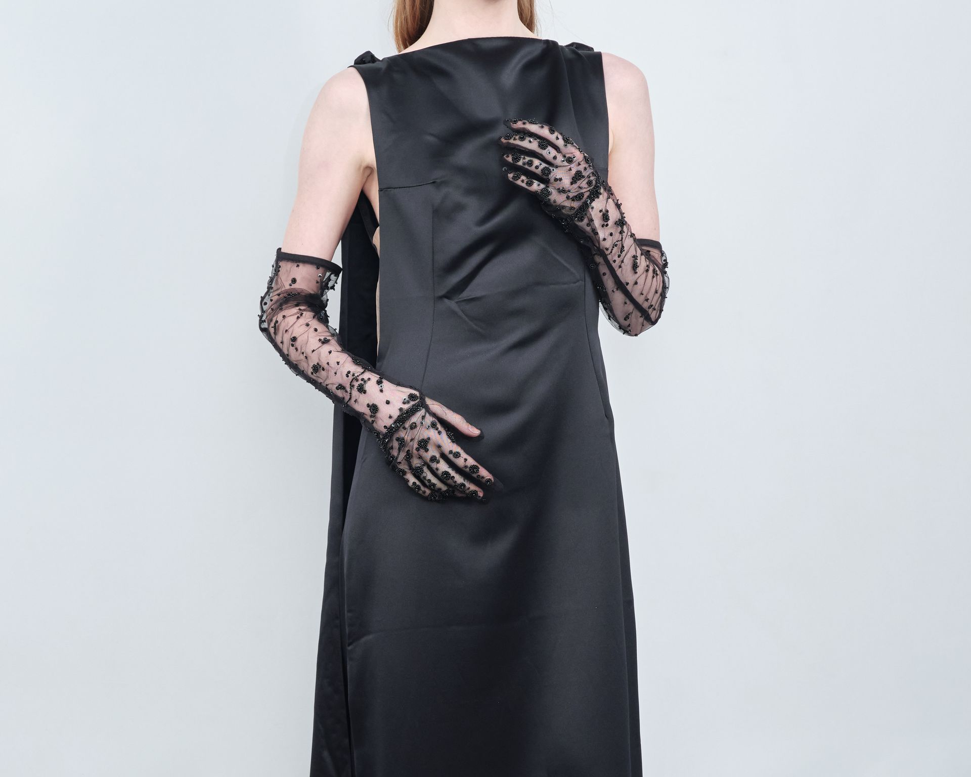 A woman wearing a black dress and long lace gloves