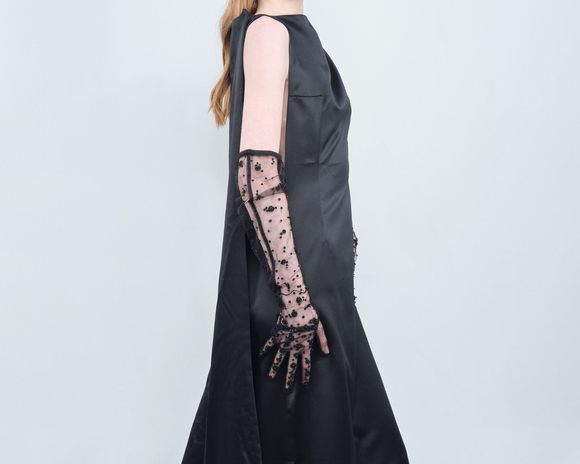 A woman wearing a black dress and long lace gloves