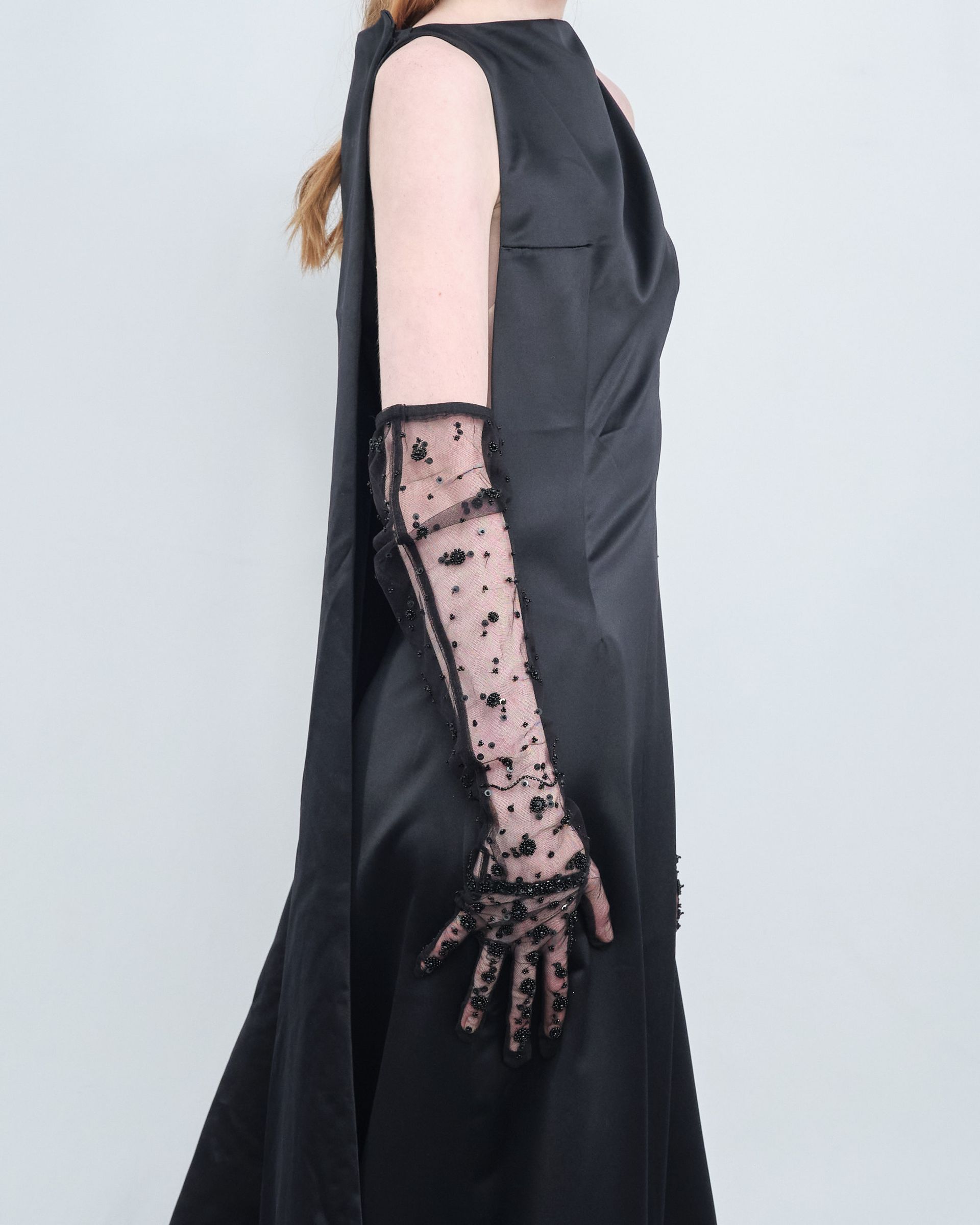 A woman wearing a black dress and long gloves