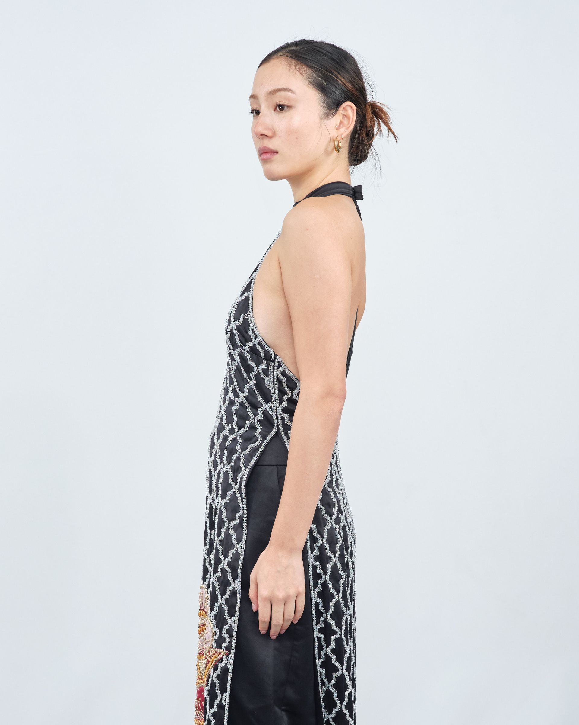 A woman in a black dress is standing in front of a white background.