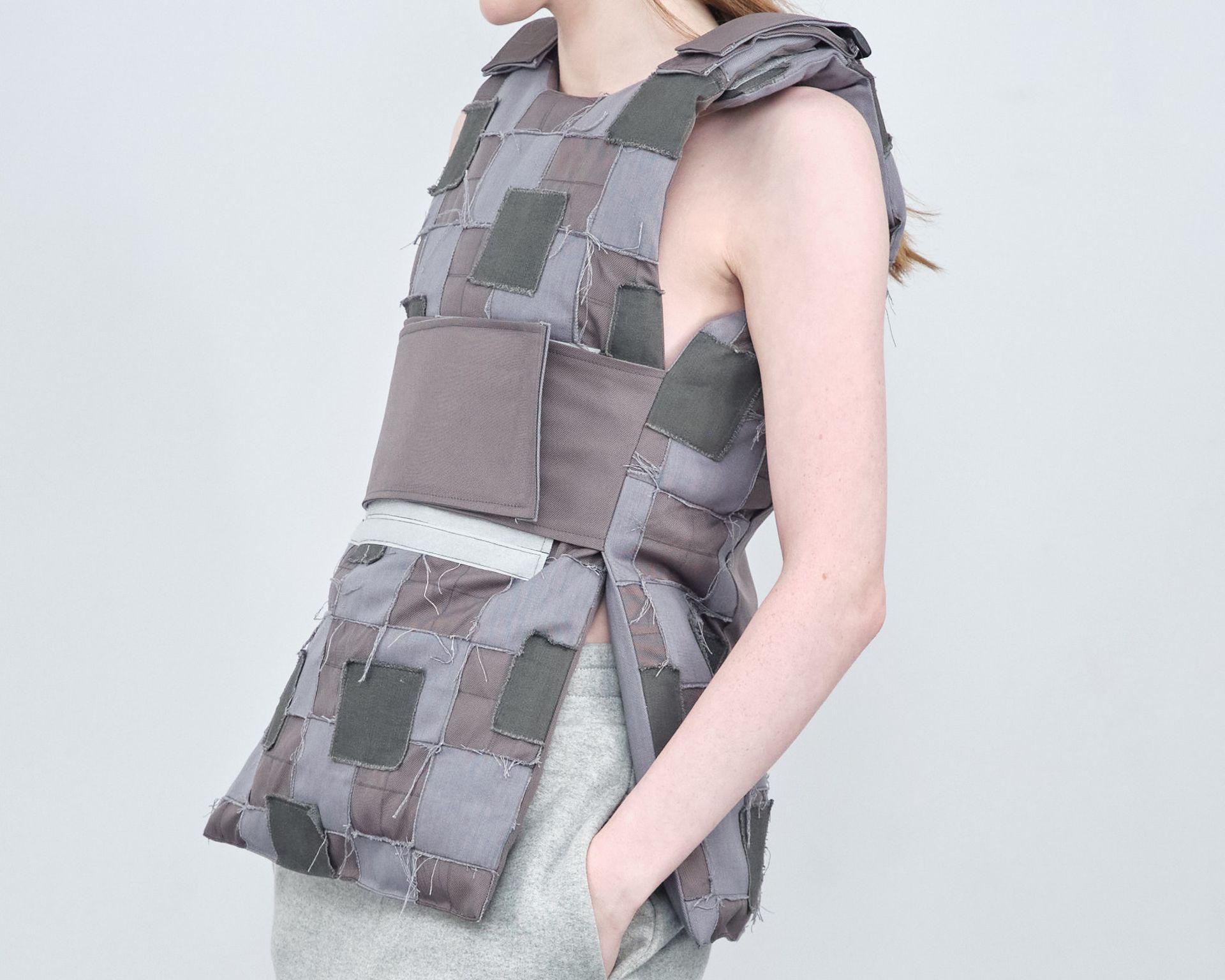 A woman wearing a grey vest with squares on it