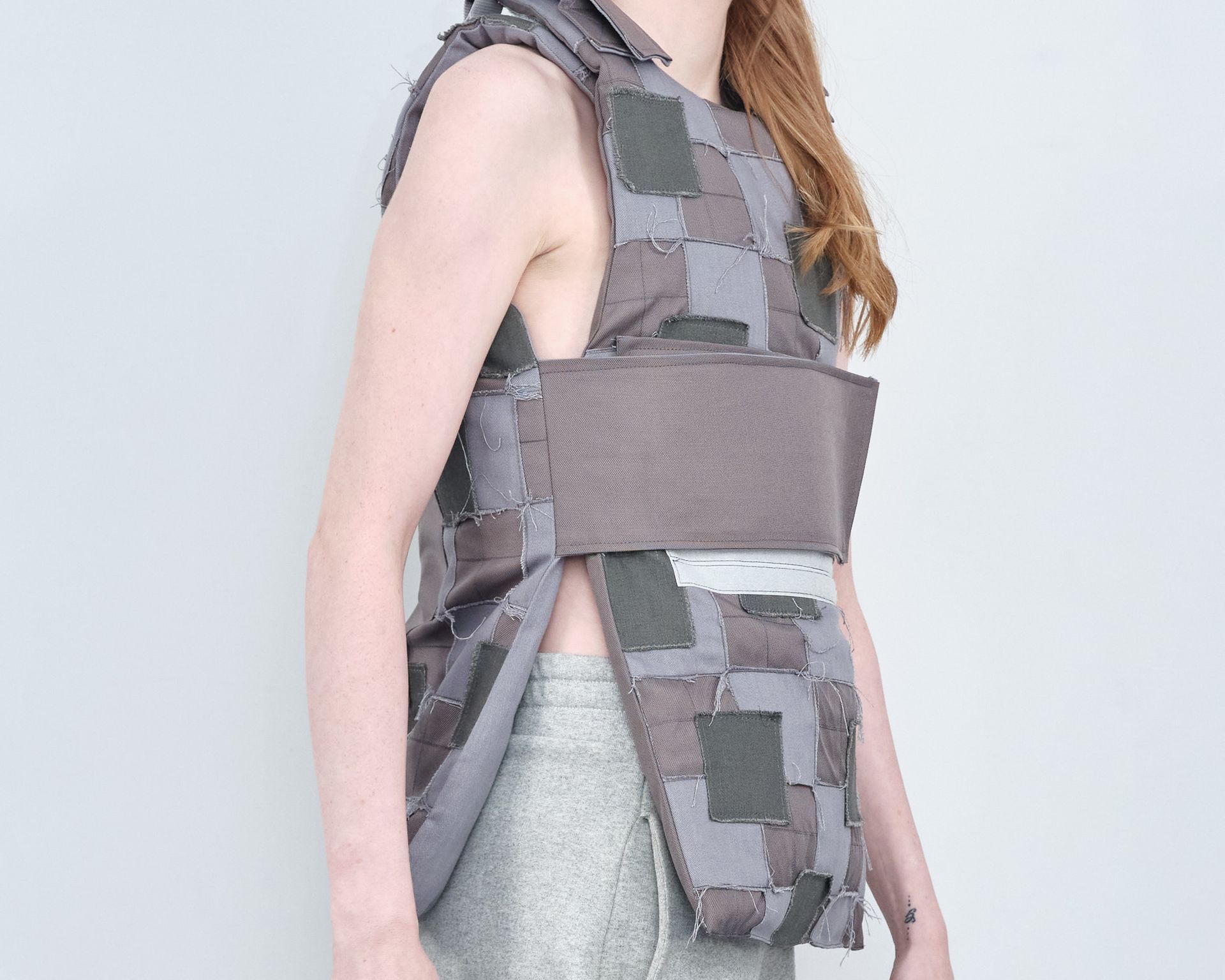A woman is wearing a gray vest with squares on it.