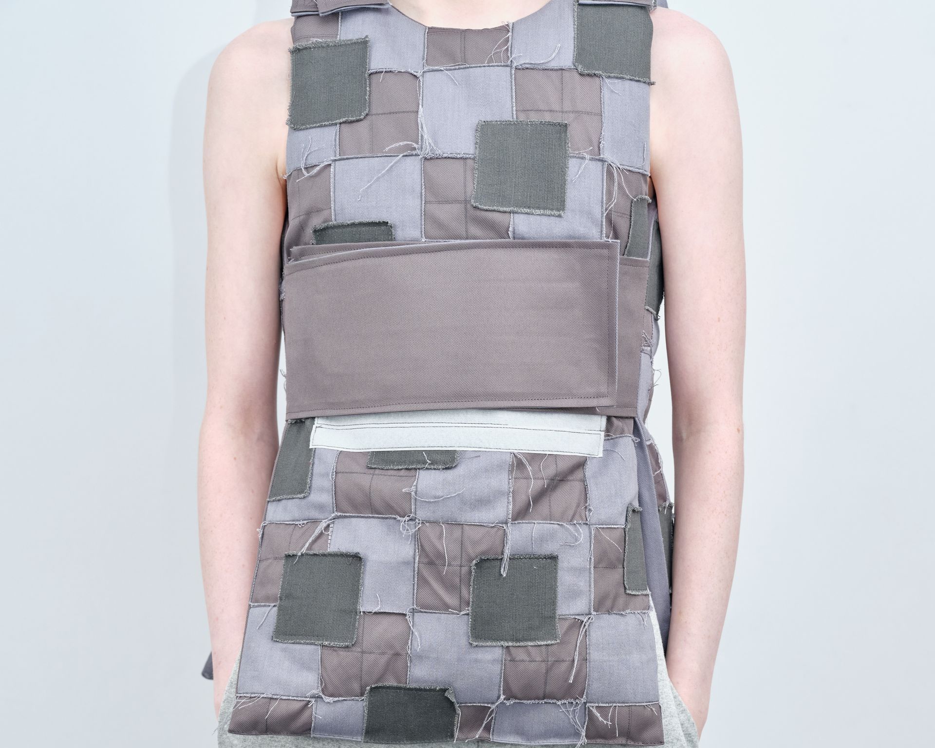 A woman is wearing a grey dress with squares on it