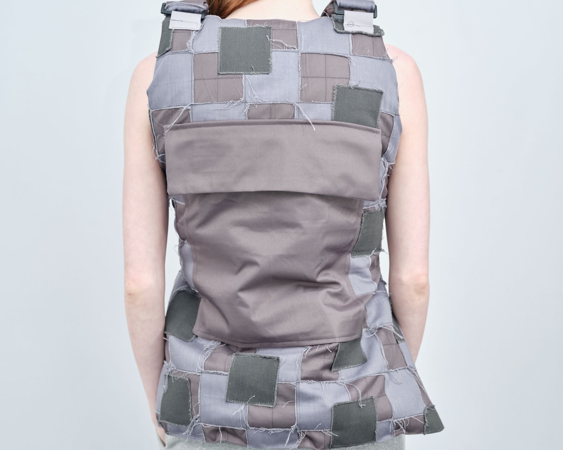 A woman is wearing a grey vest with squares on it
