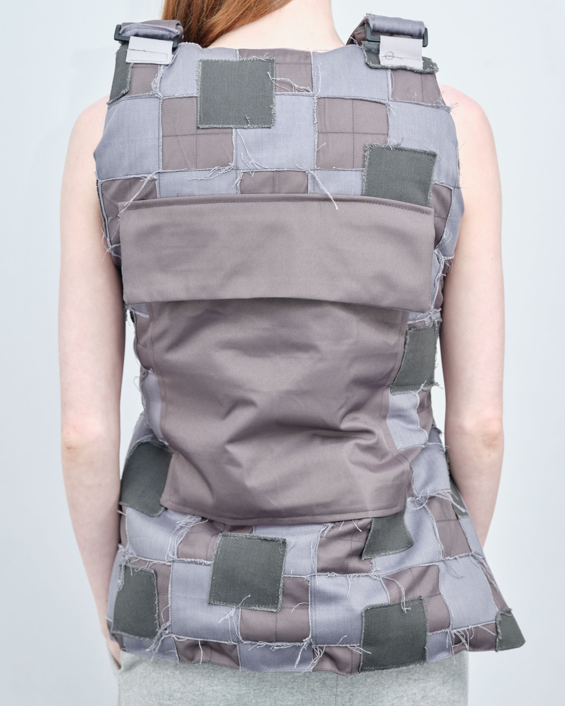 A woman is wearing a grey vest with squares on it