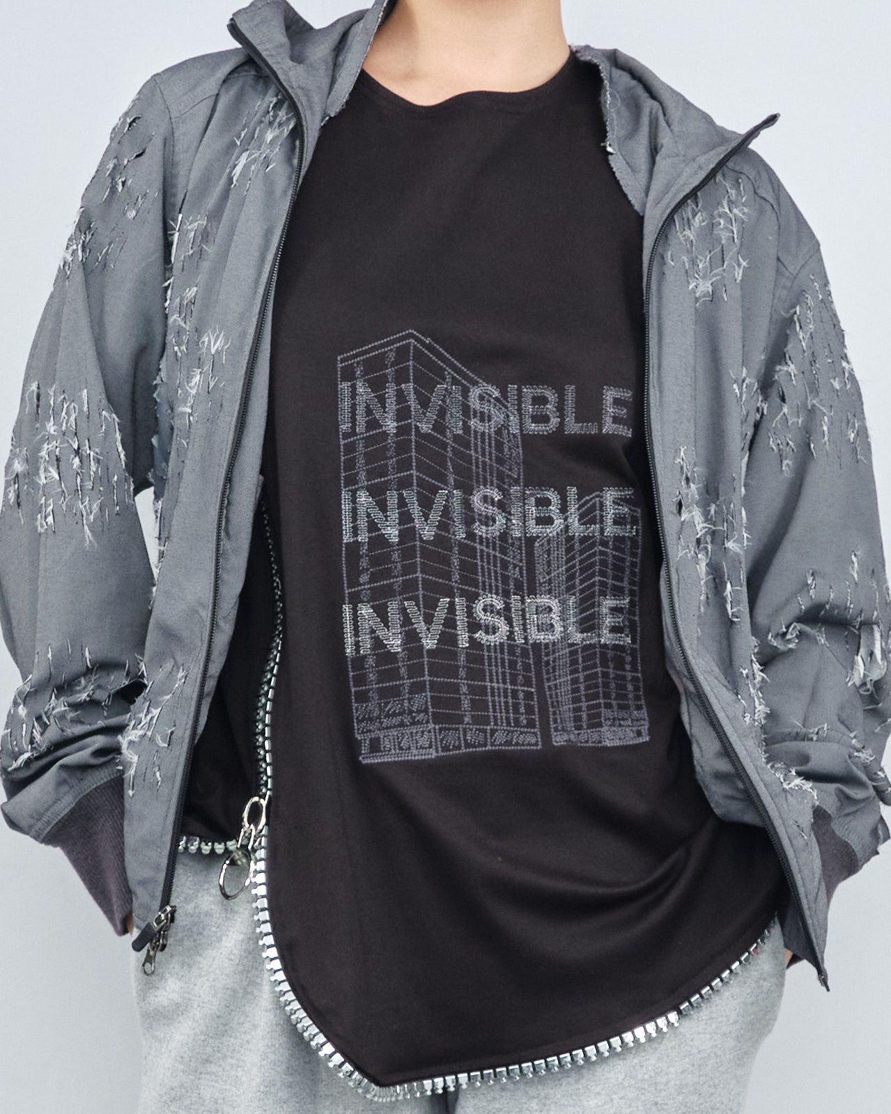 A person wearing a black shirt that says invisible
