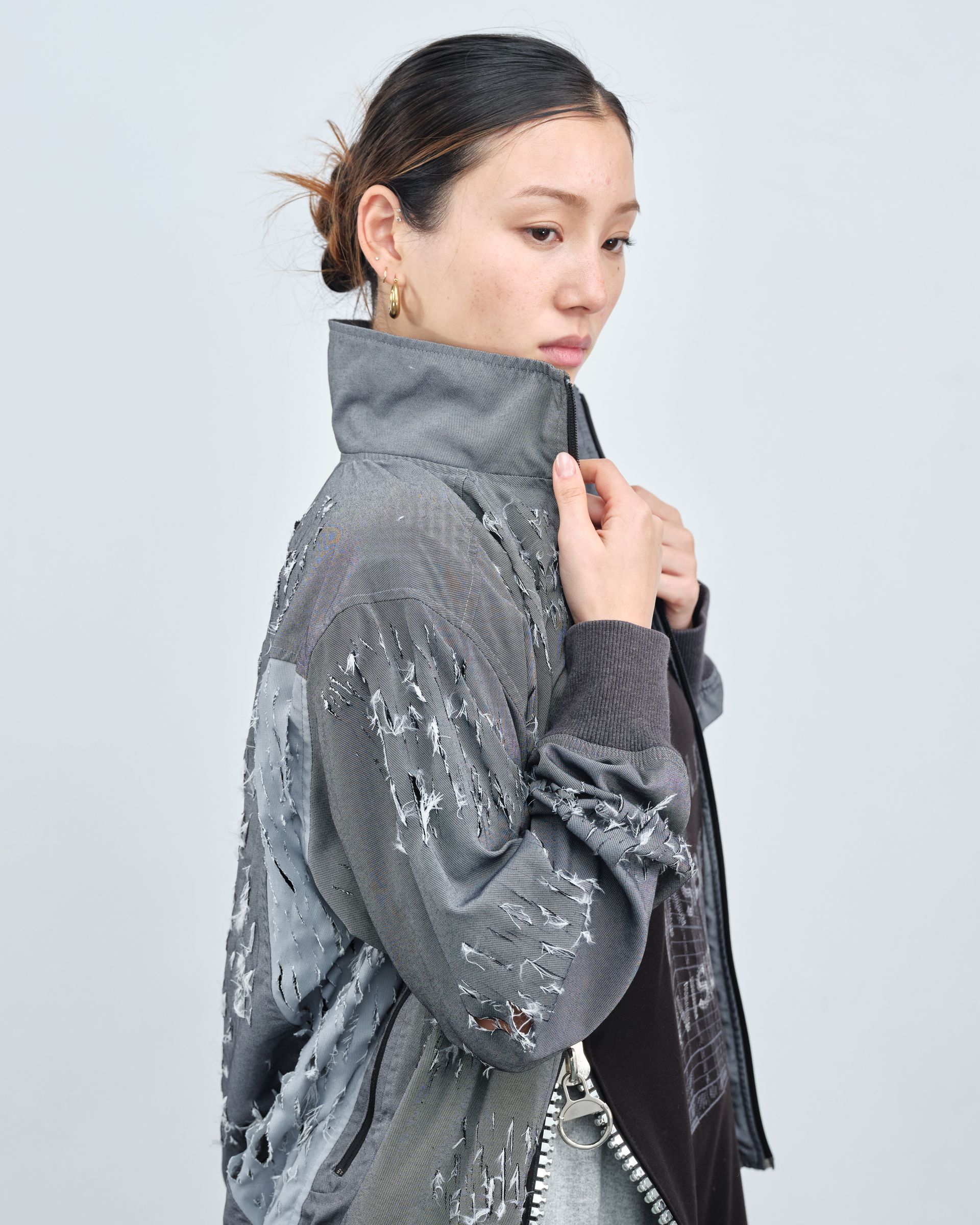 A woman is wearing a gray jacket and a black skirt.