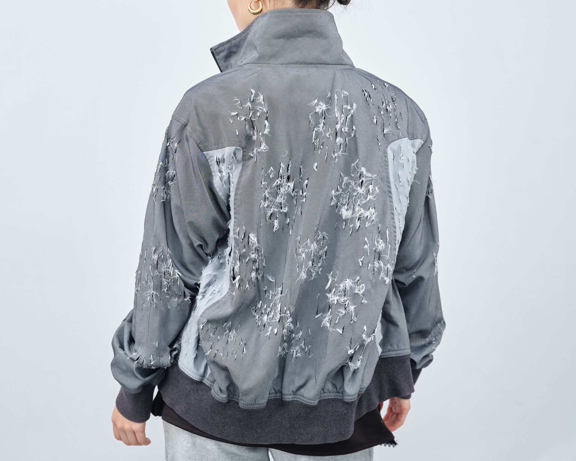 A woman is wearing a gray jacket with a floral pattern on the back.
