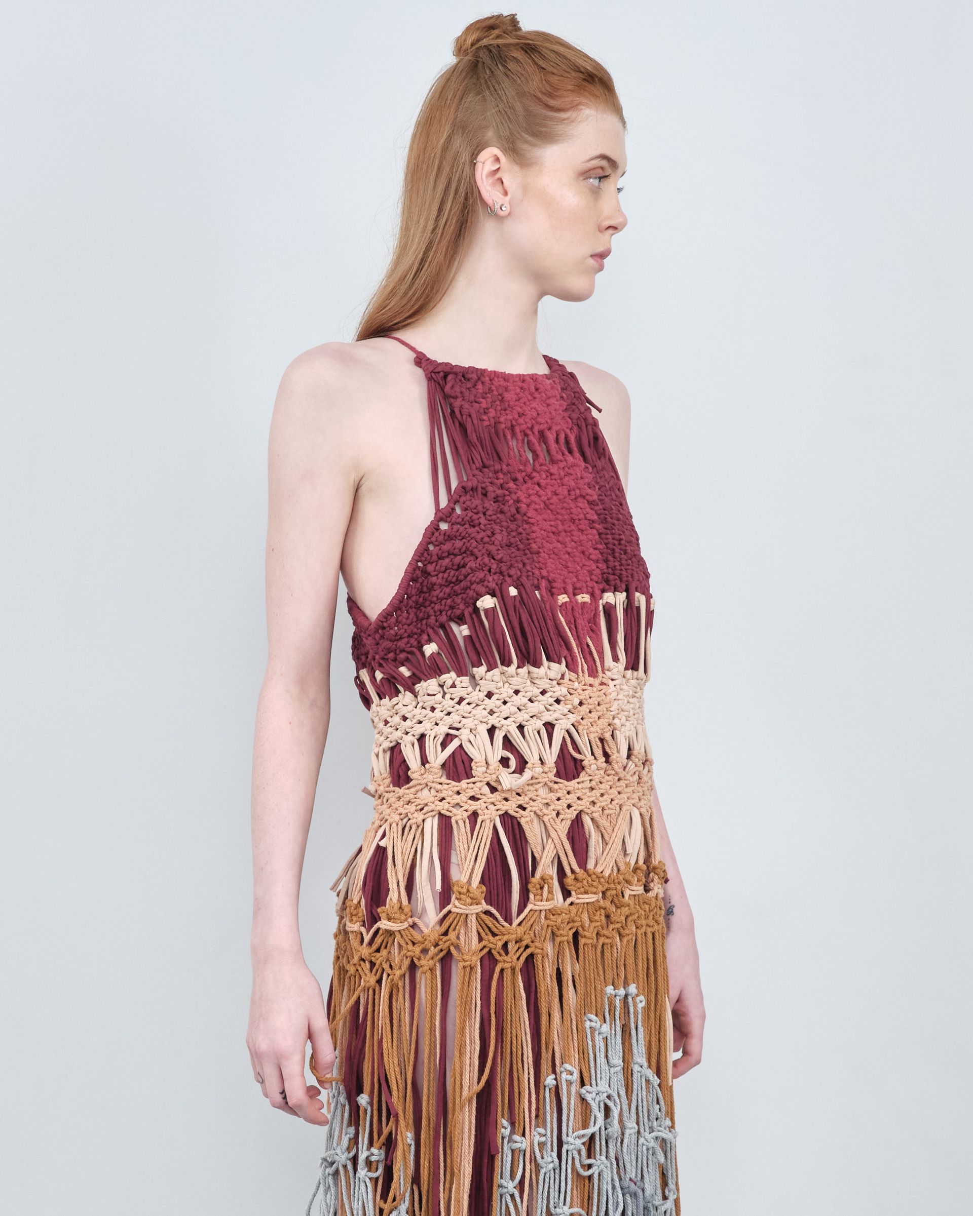 A woman is wearing a crocheted dress with fringe.