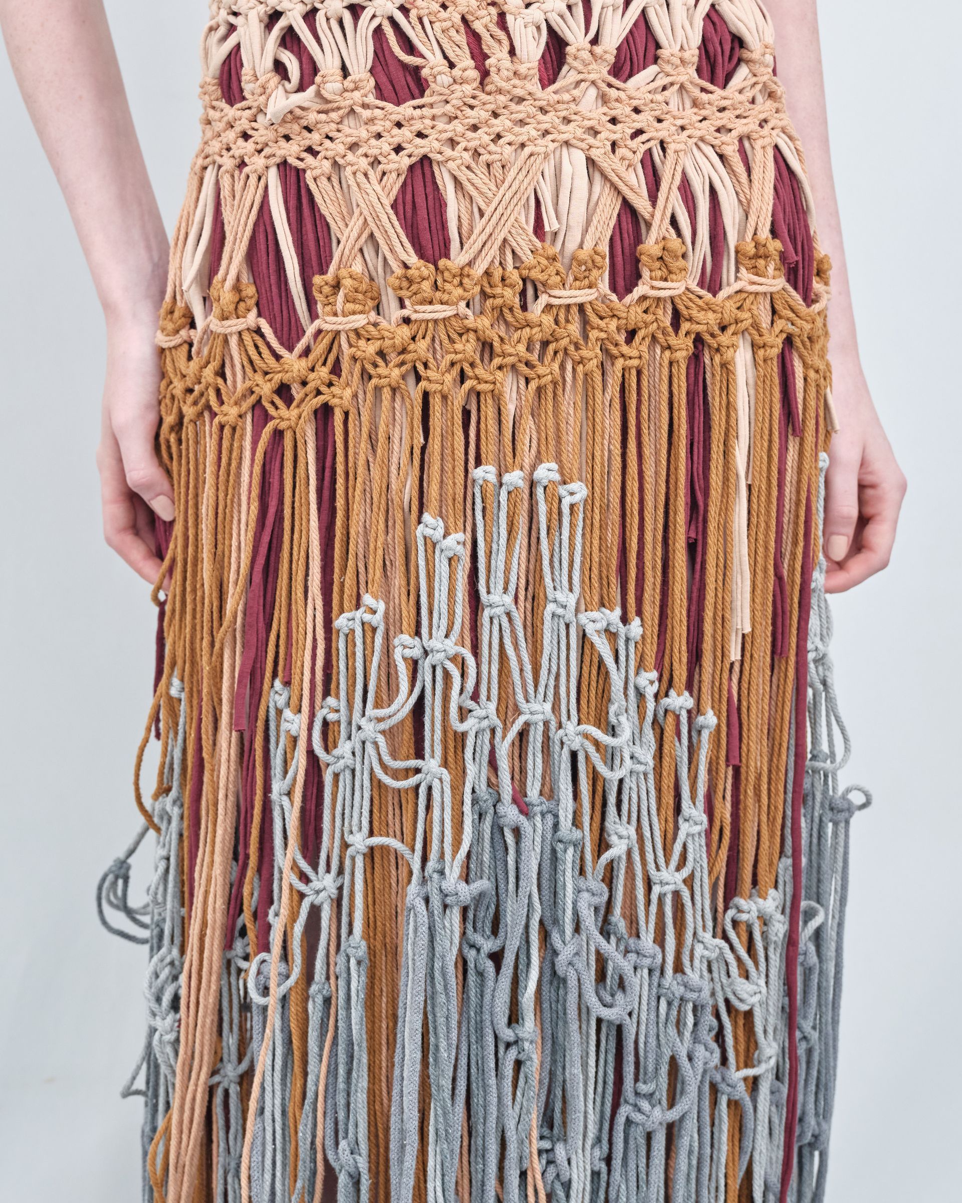 A woman is wearing a crocheted skirt with fringe