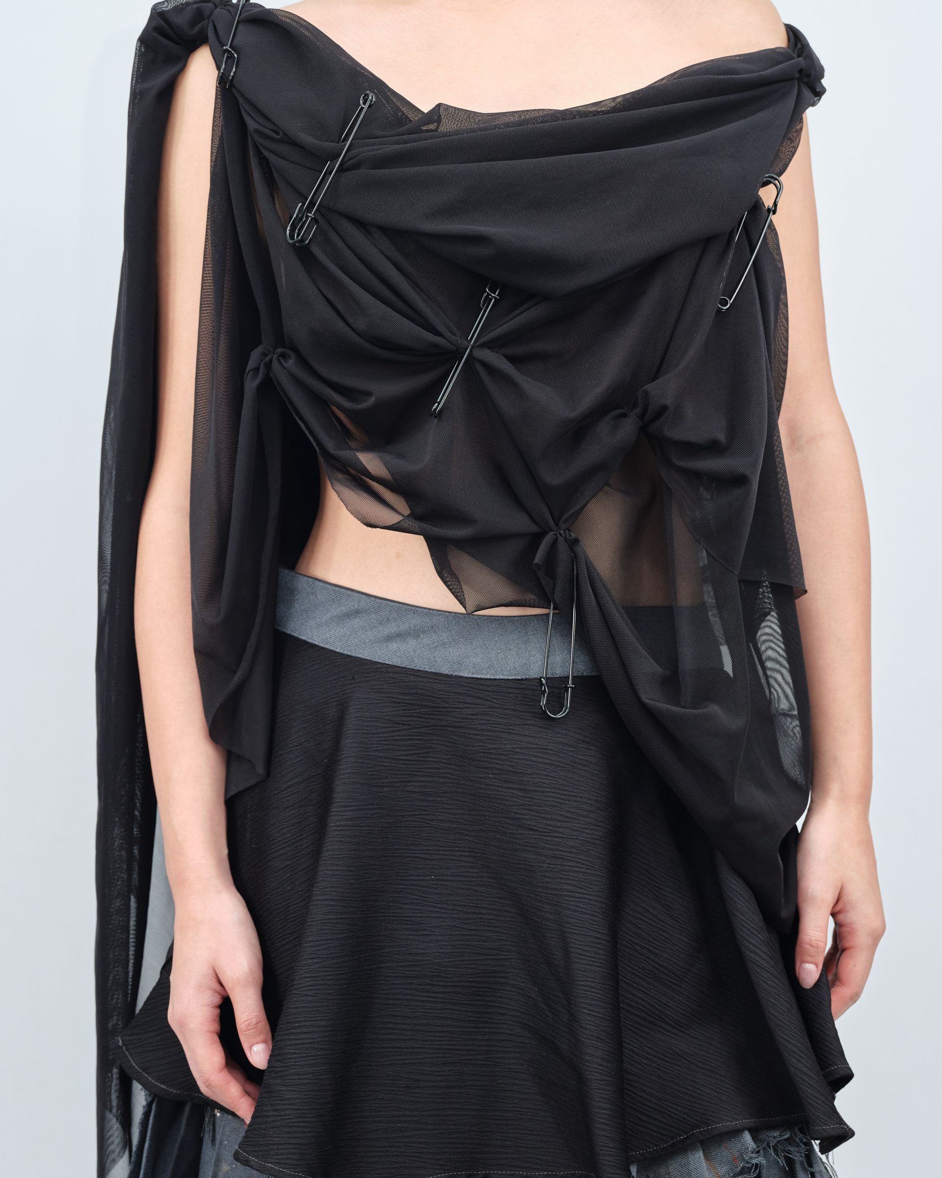 A woman is wearing a black top and a black skirt