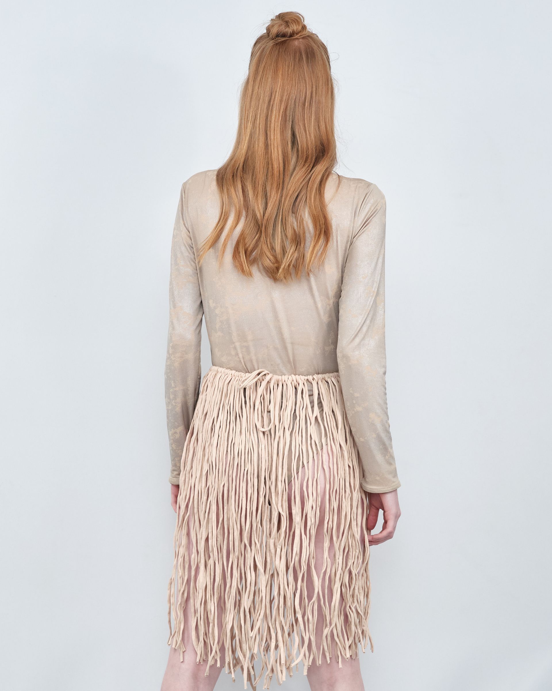 The back of a woman wearing a skirt with fringe.