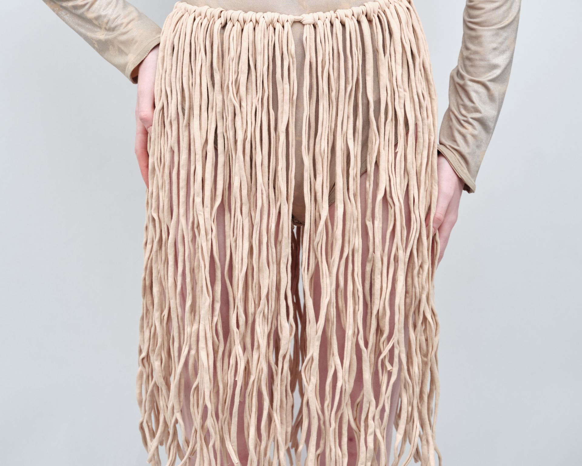 A woman is wearing a tan skirt with fringe
