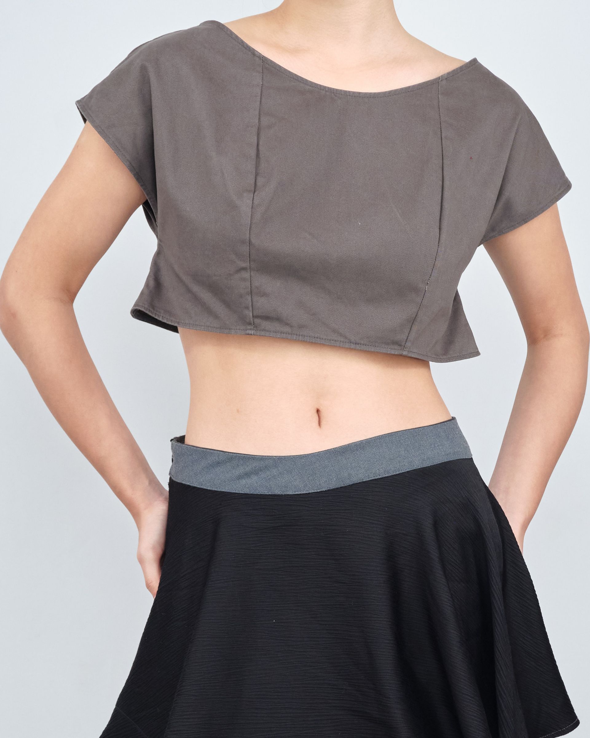 A woman is wearing a crop top and a black skirt