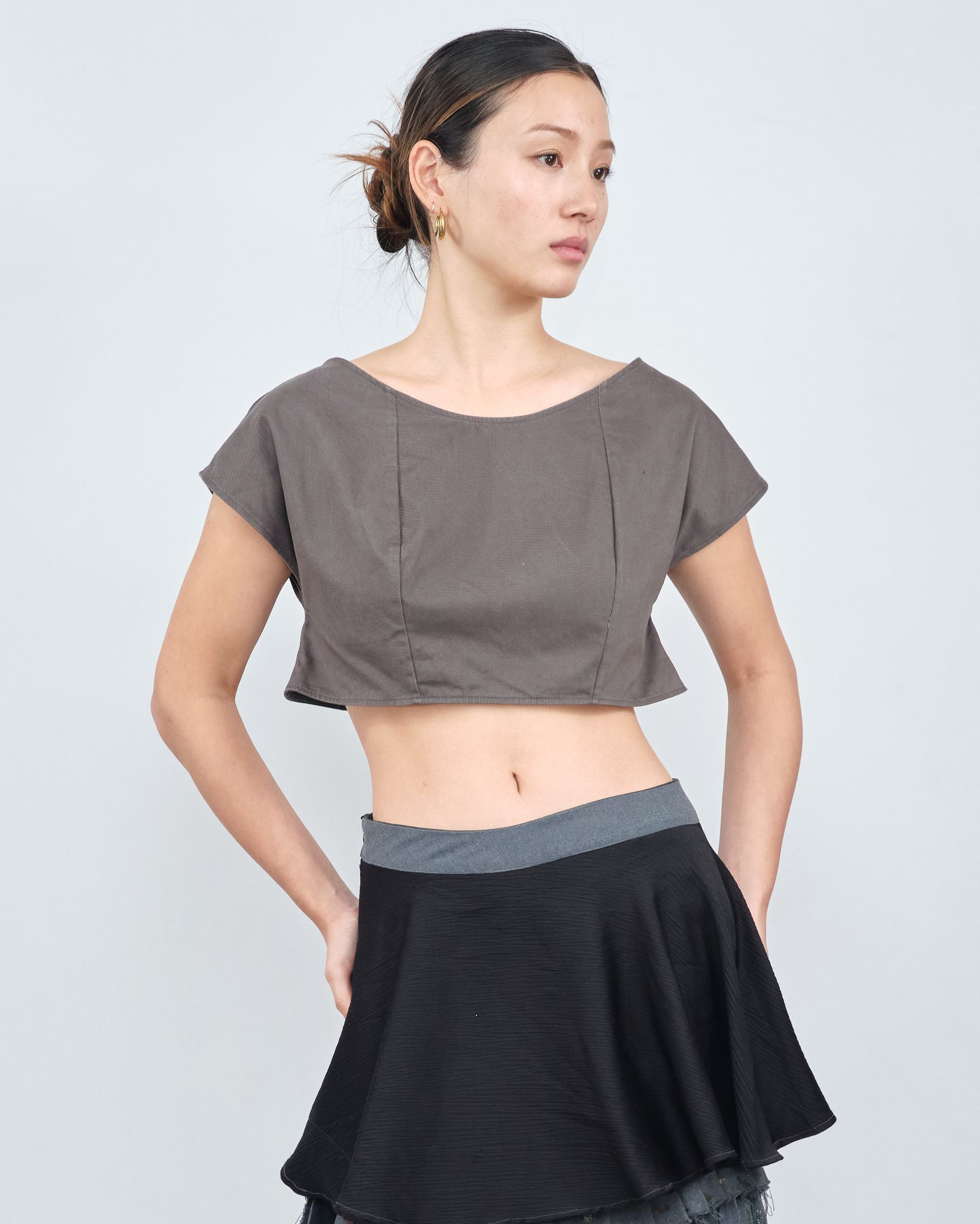 A woman is wearing a crop top and a black skirt.