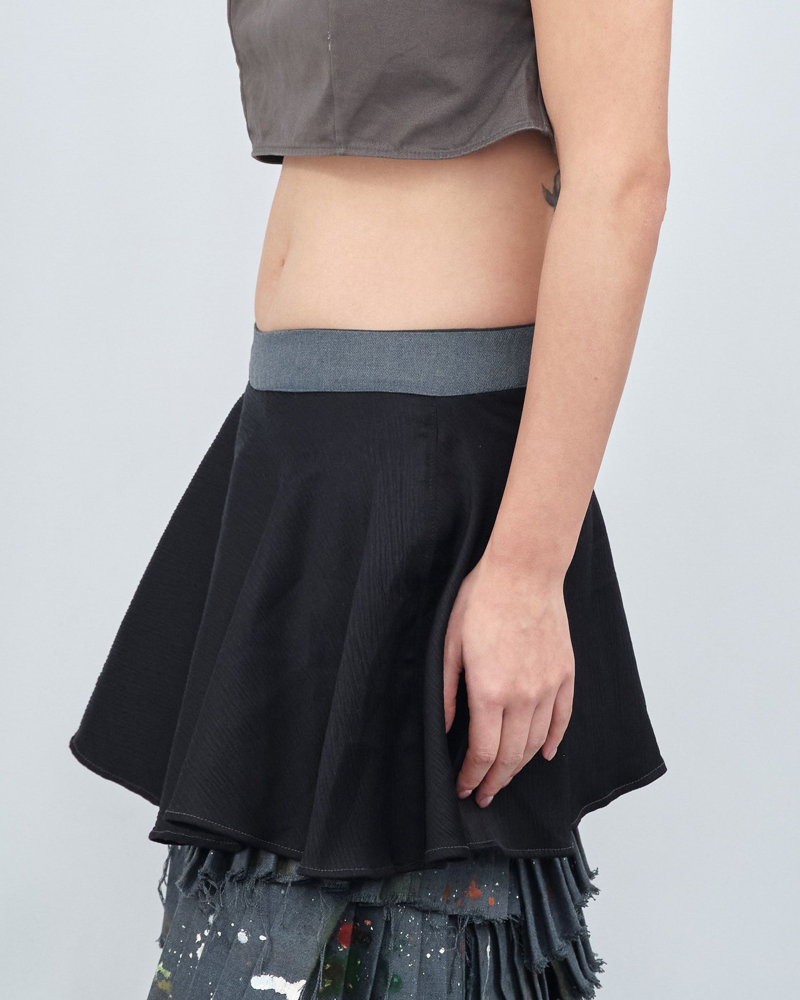 A woman is wearing a crop top and a black skirt.
