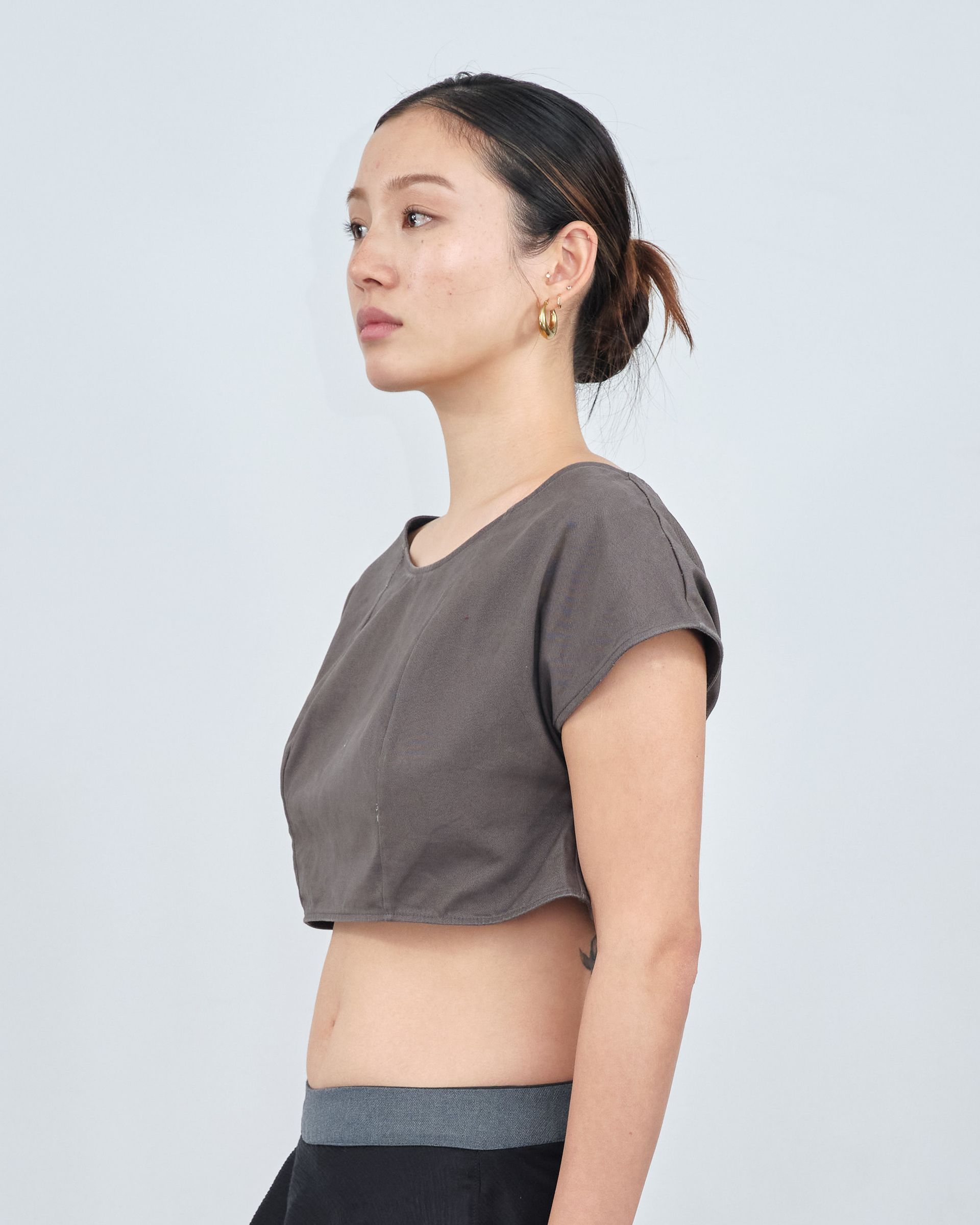 A woman is wearing a crop top and earrings.
